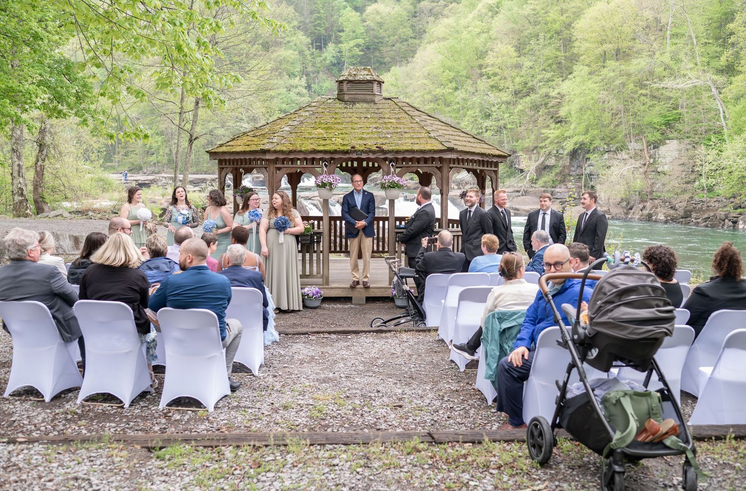 candid wedding photo: guests seated in white chairs waiting for the bride to arrive, with a gazebo in the background