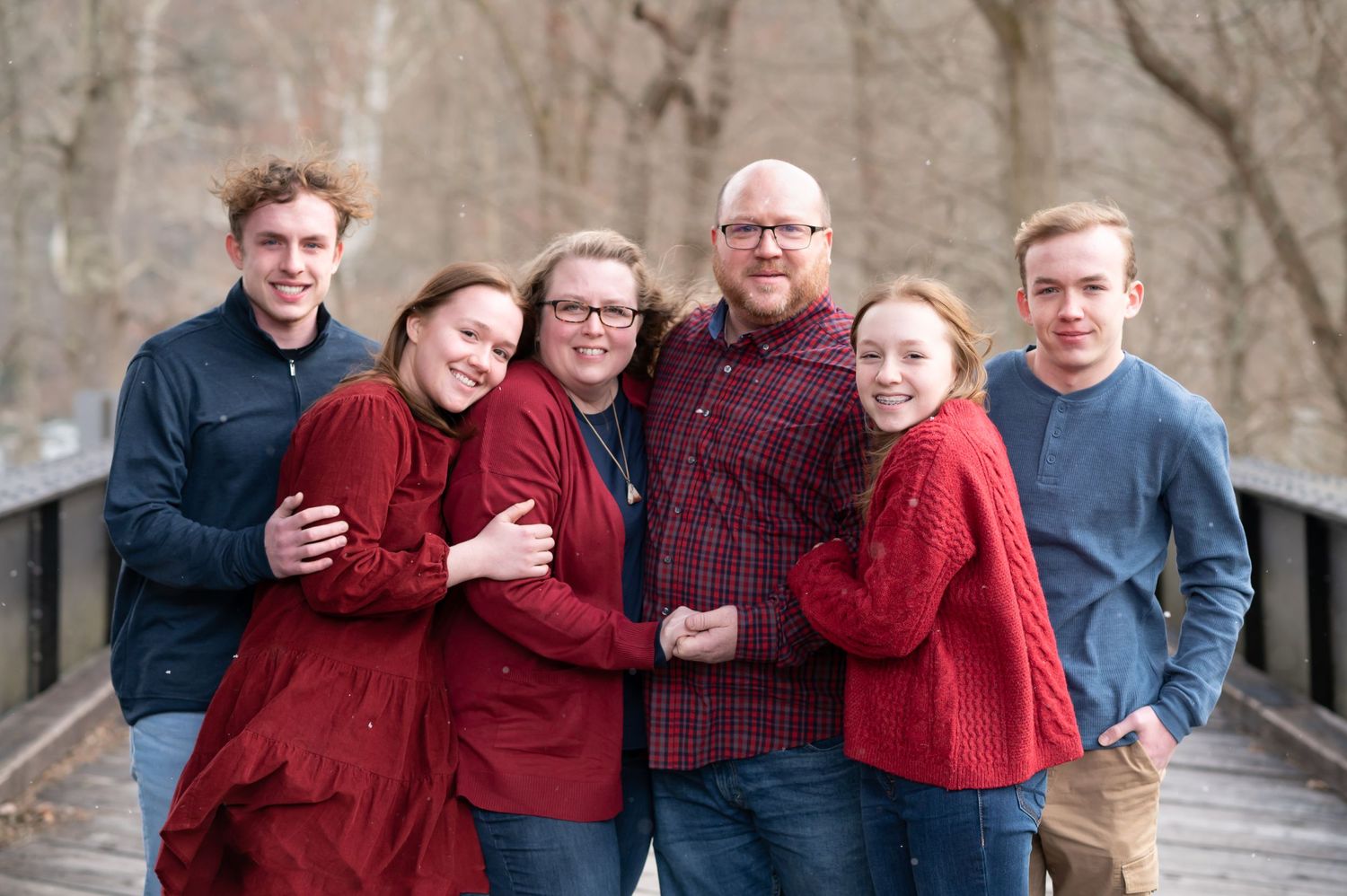 a family of five with teenage children huddle together in sweaters with smiles for a cold outdoor winter portrait in Fairmont, WV