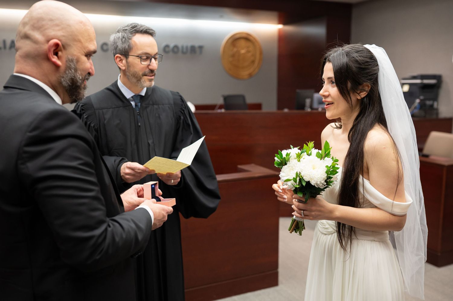 a bride and groom smile at a judge as he conducts their wedding ceremony at a courthouse wedding in Morgantown, WV