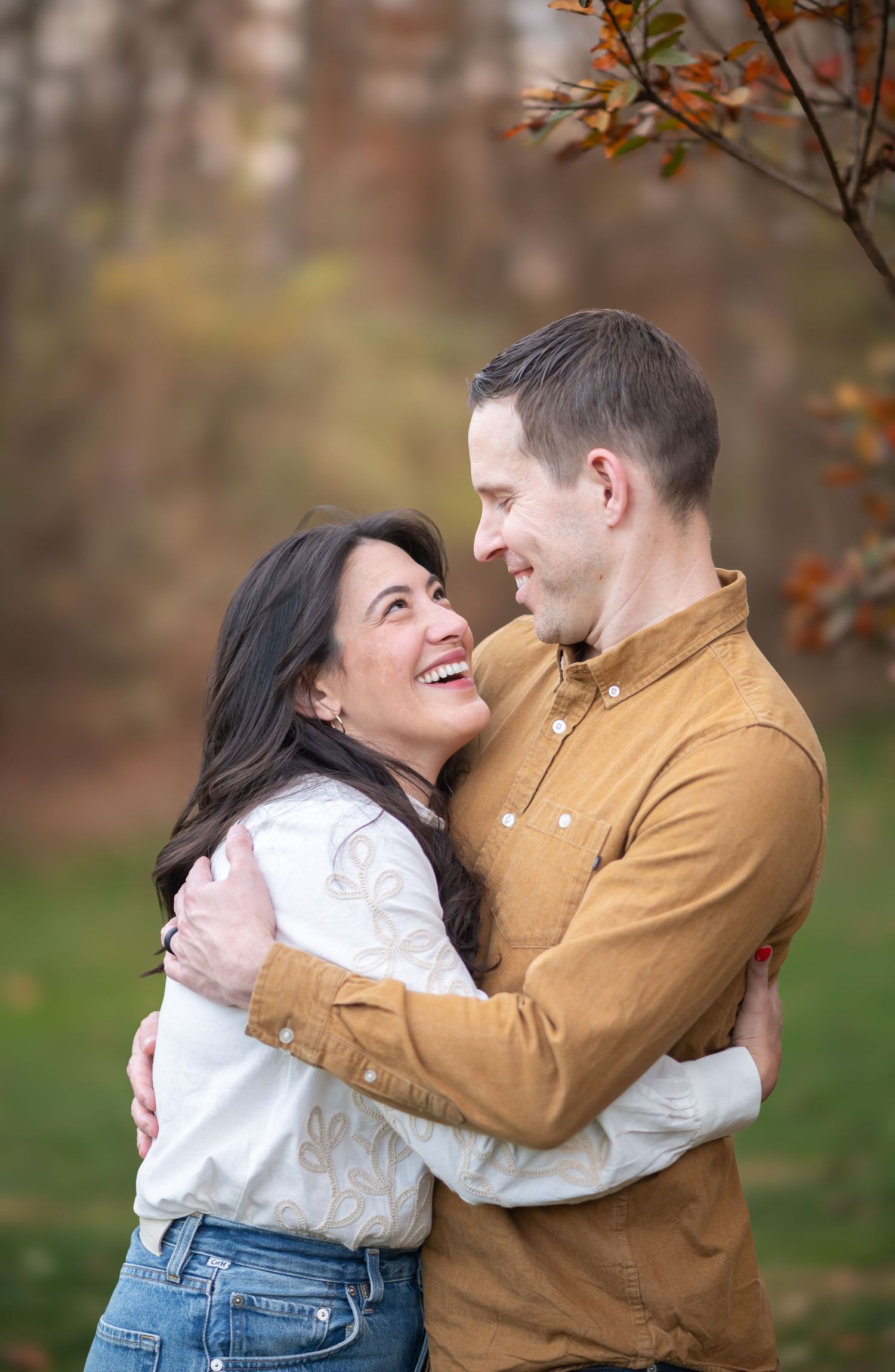 a beautiful couple hold each other and laugh, with autumn leaves in the background; shot at the clients' home in Morgantown, WV