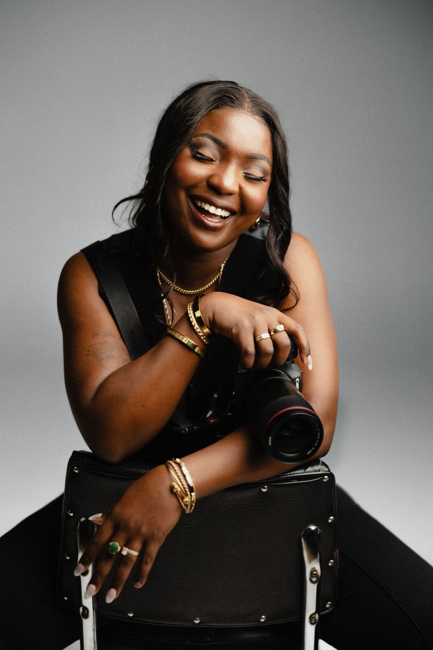 woman holding camera and smiling with eyes closed