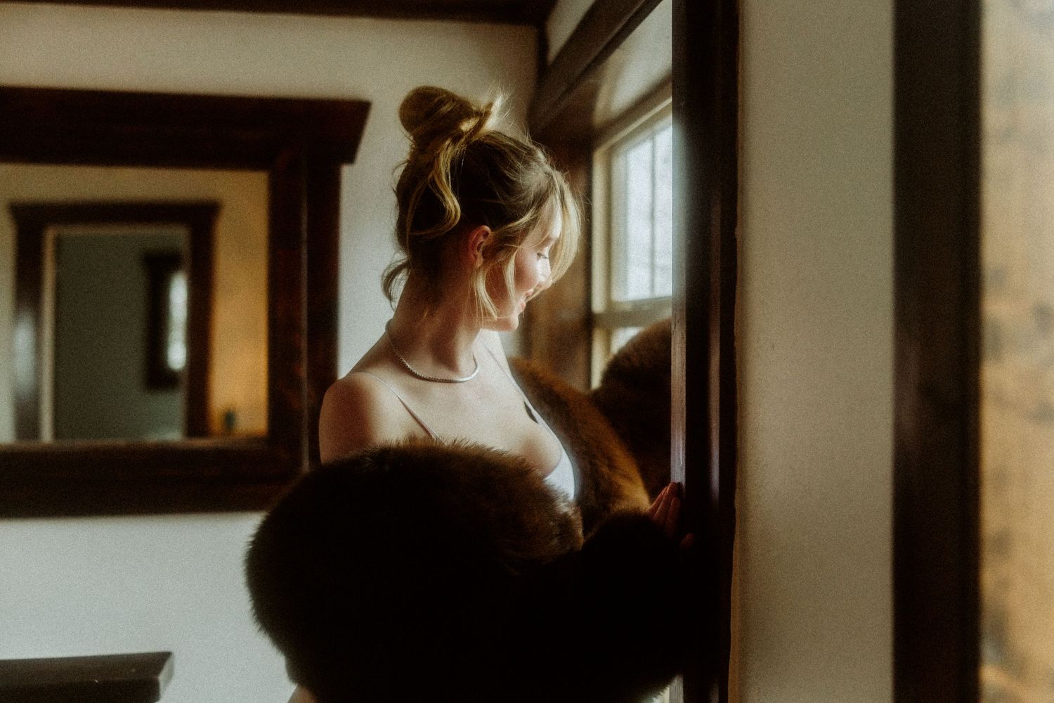 A silhouette figure stands by a window in soft, dreamy lighting.