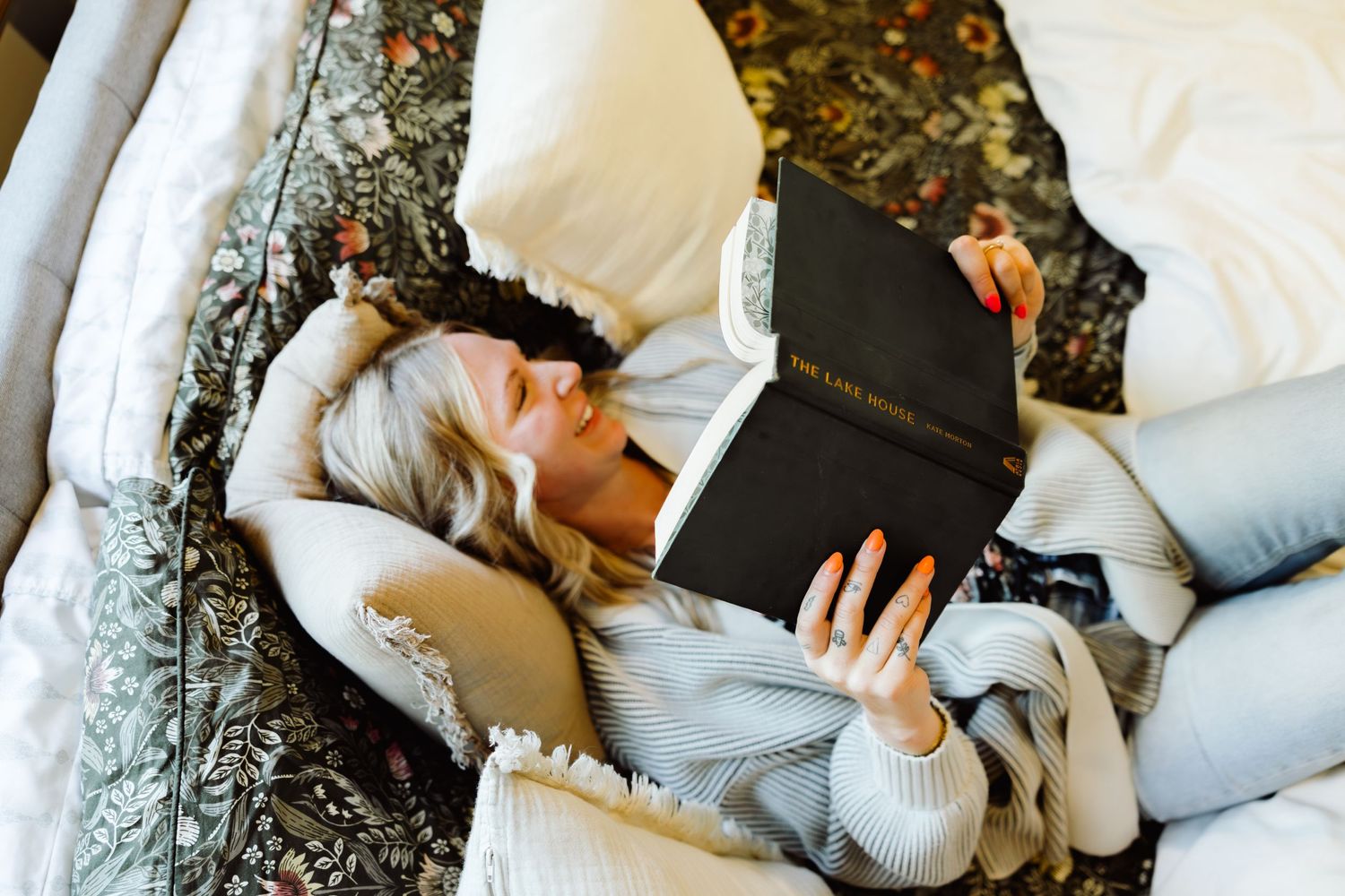 girl laying down with book and smiling