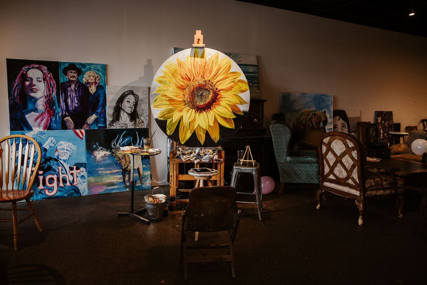 Art studio display featuring large sunflower painting and multiple canvases.