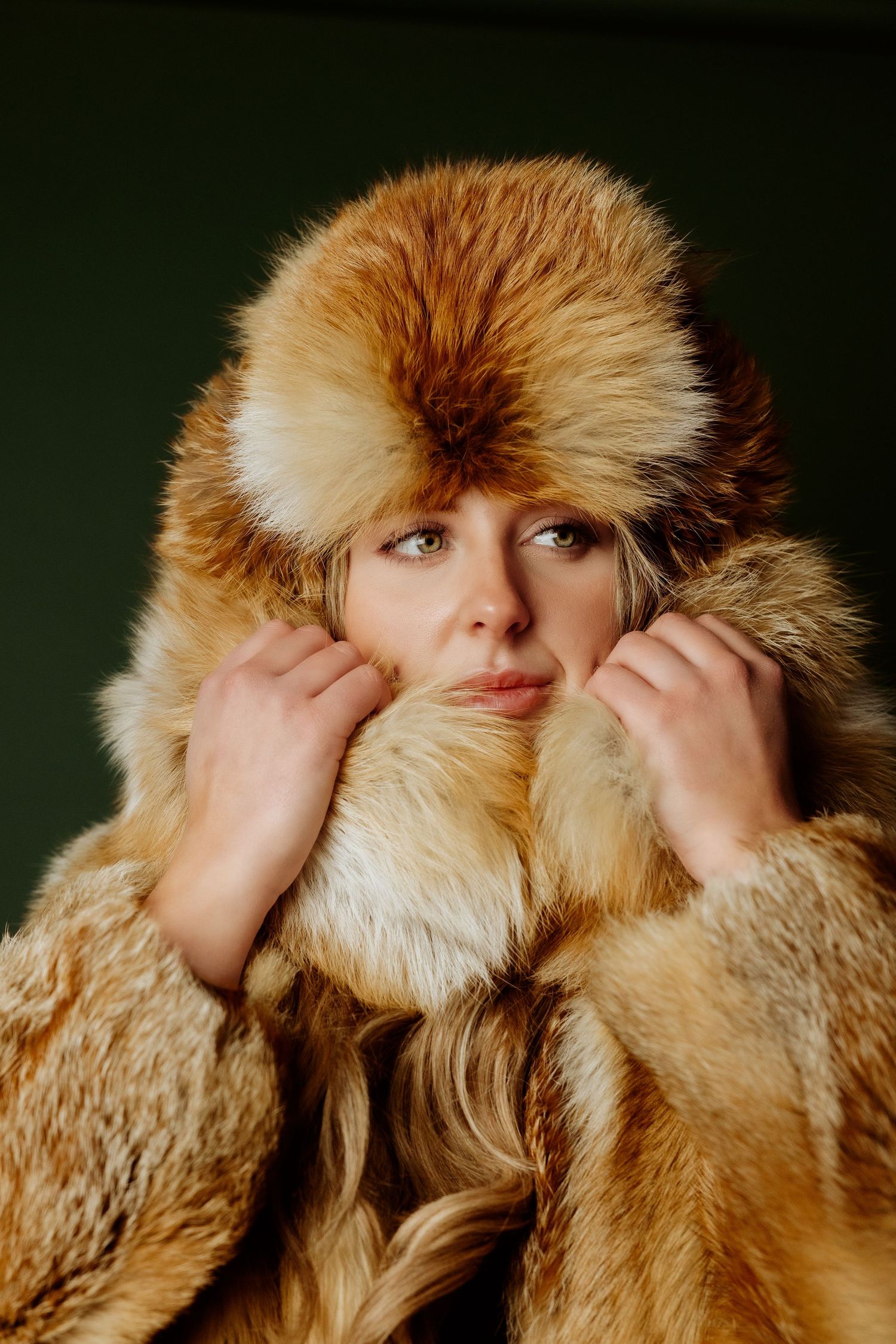 Model wearing a luxurious brown fur coat and matching fur hat in a vintage-style portrait against dark background.