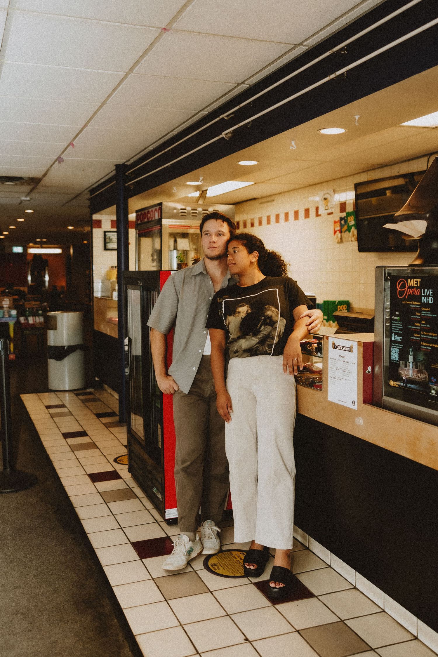 Casual couple standing together in retro-style diner interior with checkered floor.