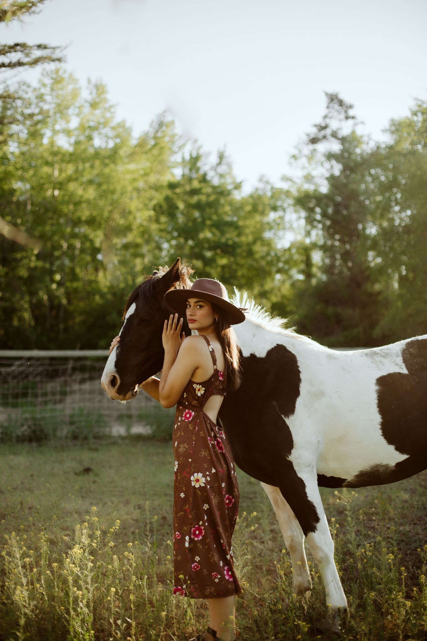 Girl holding her horse in sunset