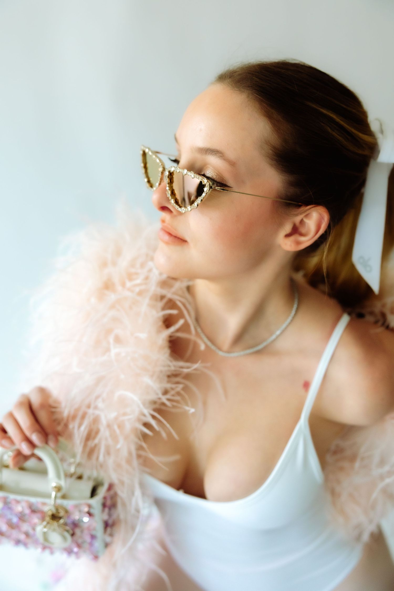 Glamorous portrait with soft pink feather boa and metallic sunglasses.