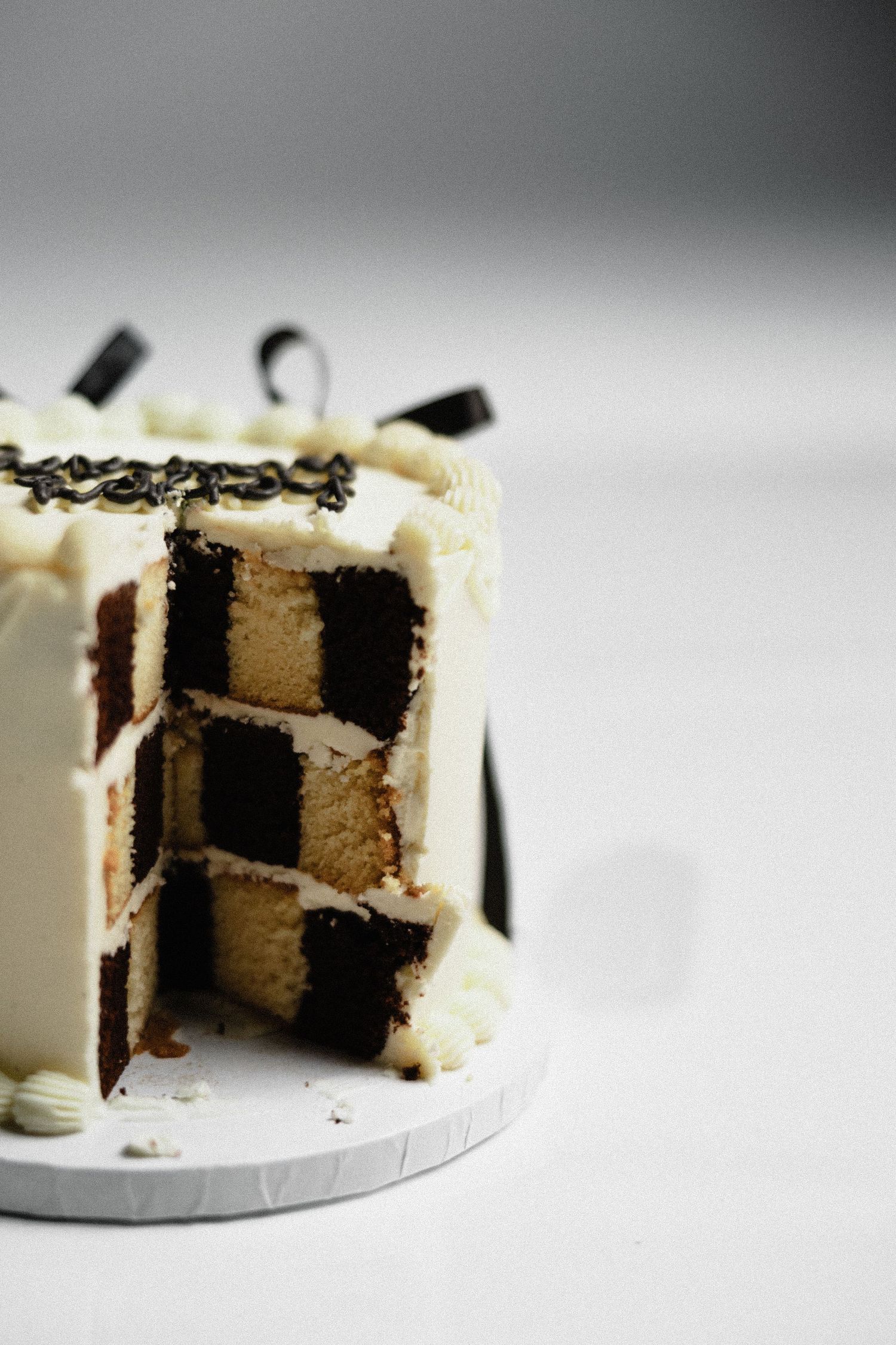 Elegant checkerboard pattern cake with black and white layers decorated with chocolate shavings.