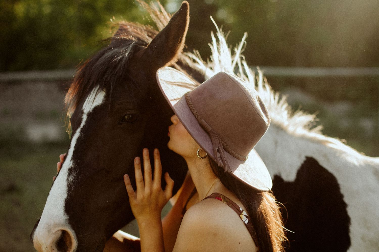 Girl holding her horse in sunset