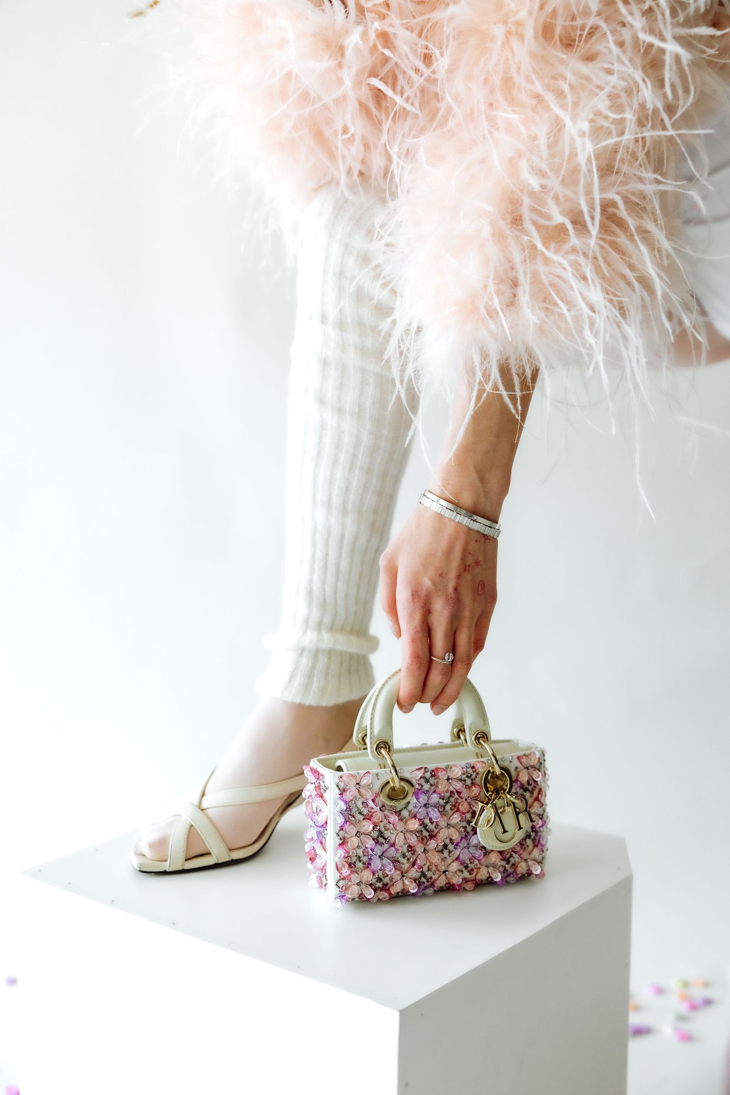 Feminine fashion detail of sparkly handbag and high heel with feather accents.
