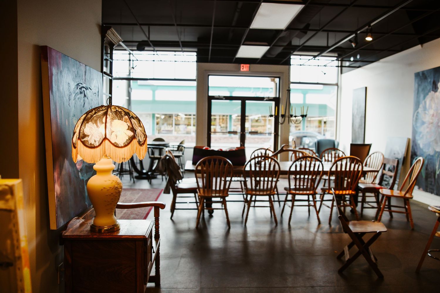 Empty restaurant dining room with vintage table lamp and wooden chairs.
