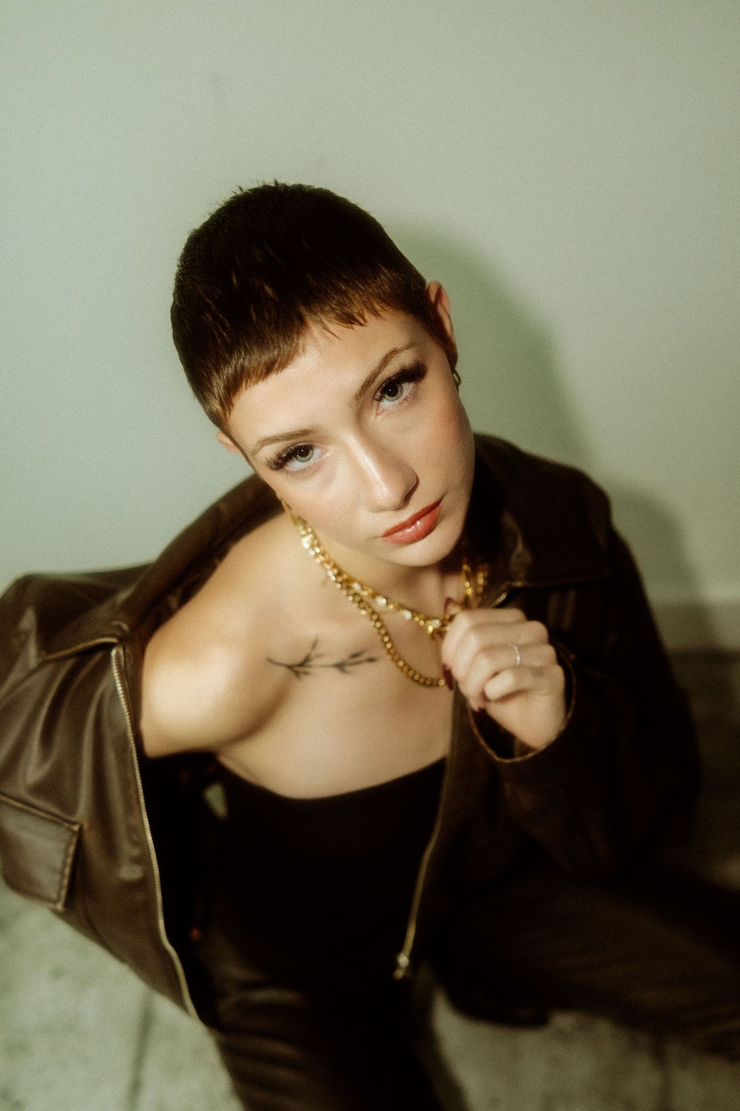 Moody fashion portrait with gold jewelry and dark attire in vintage style.