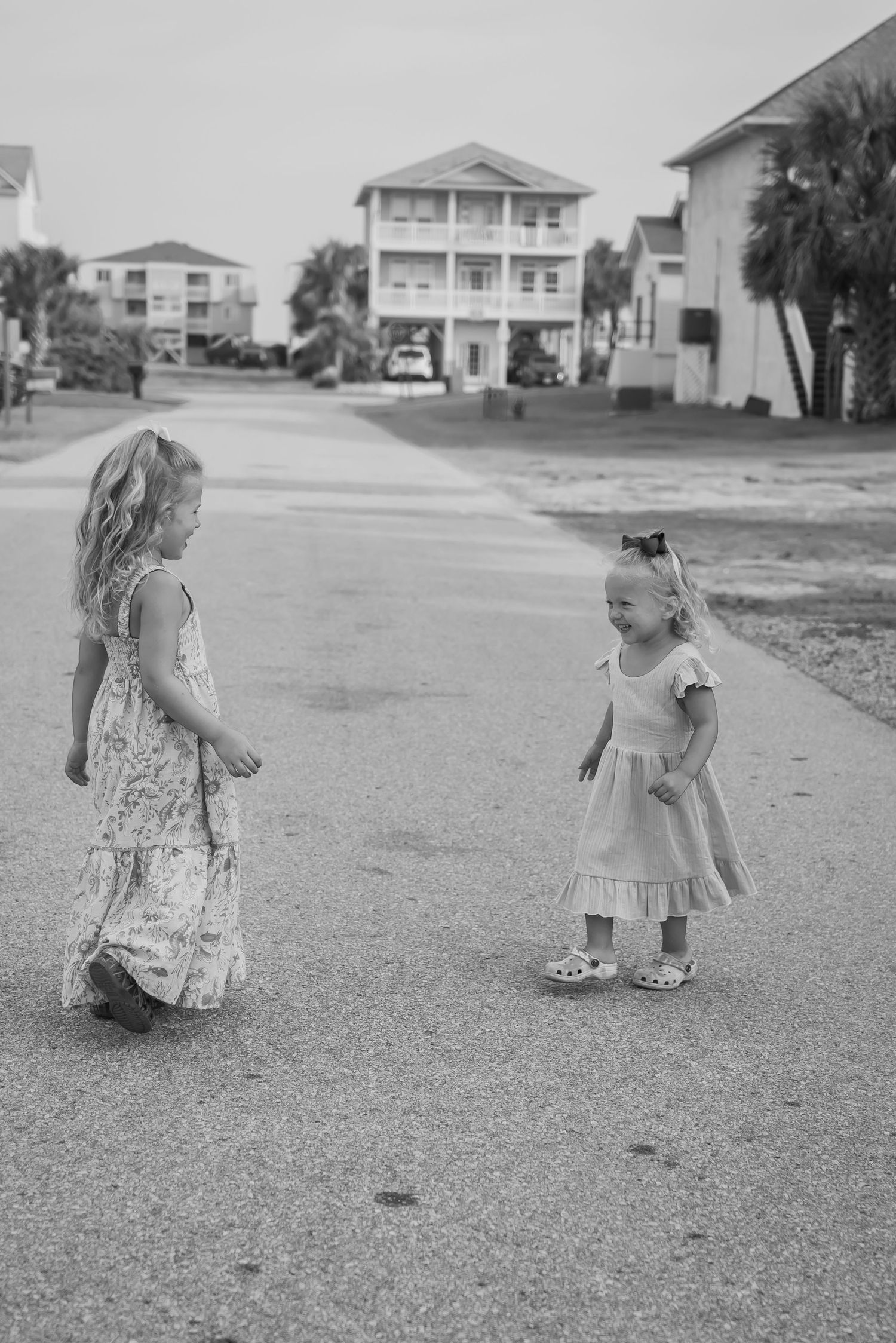 Black and white sequence of children walking on a street with beach houses in background.