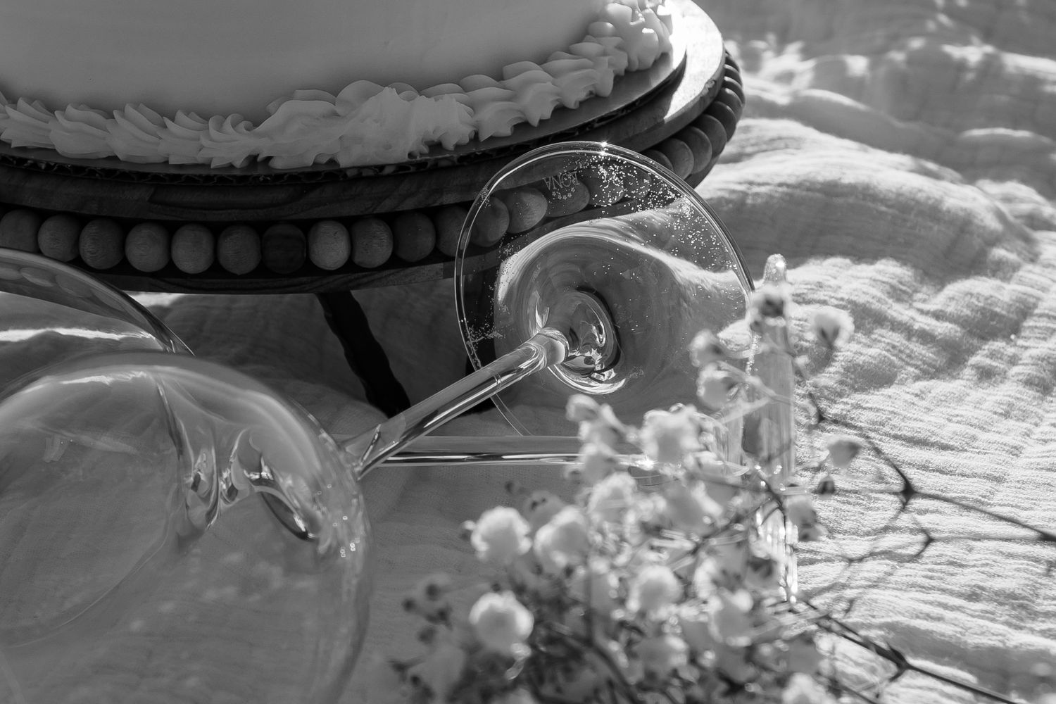 Vintage-style black and white photo of cake stand with delicate lace and baby's breath flowers.