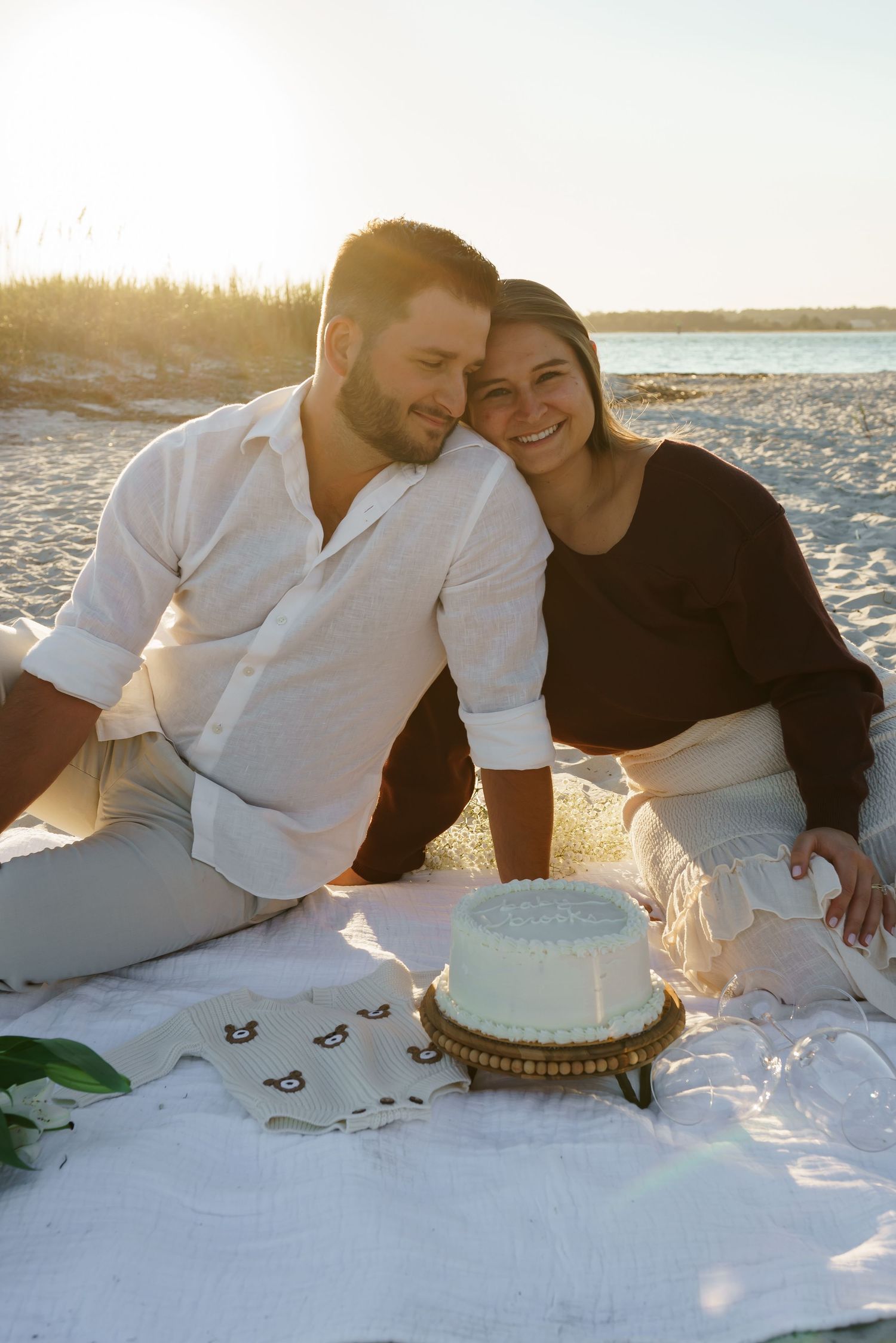 Couple having romantic picnic on beach blanket at sunset.