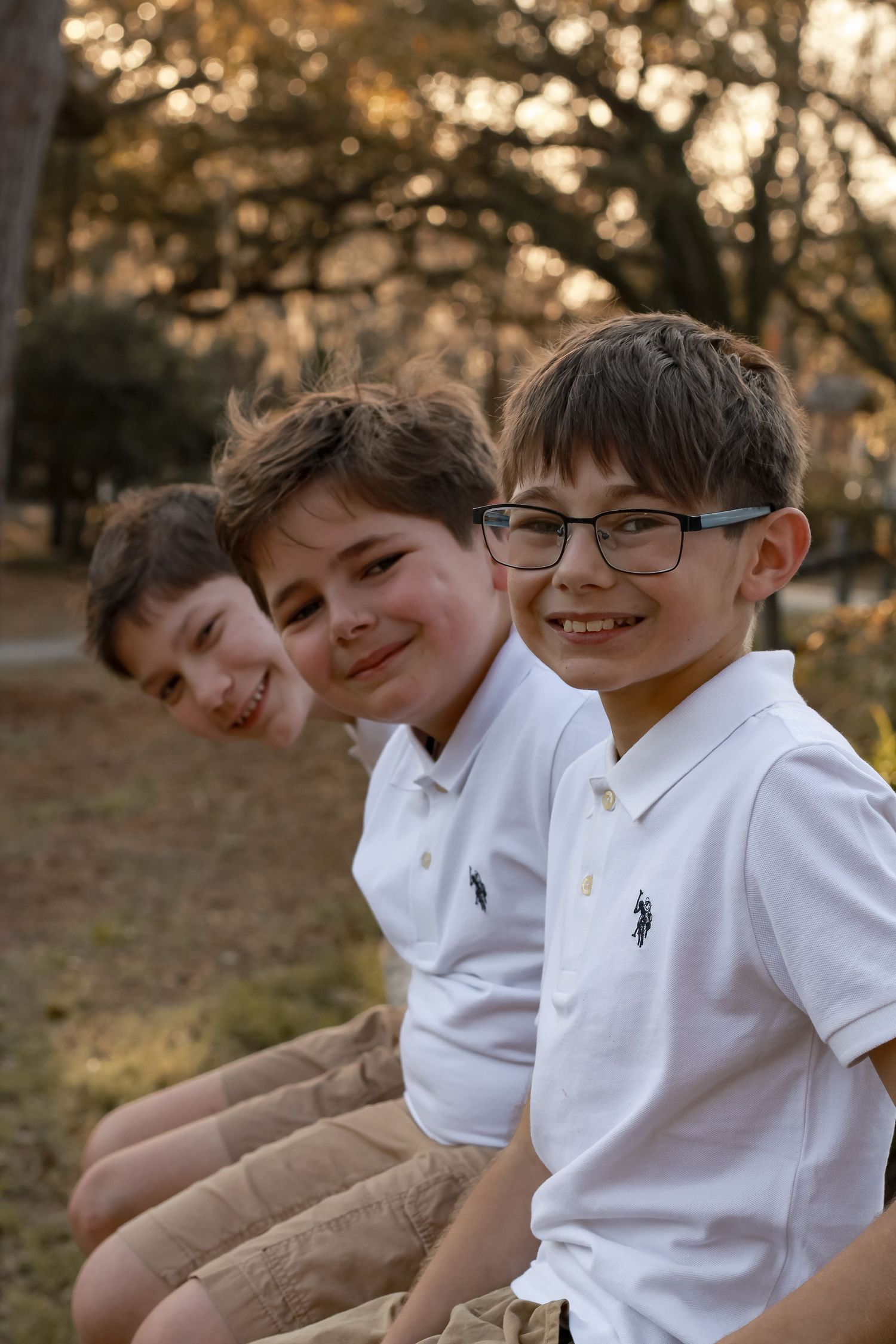 A series of outdoor portraits showing young boys in white polo shirts sitting together.