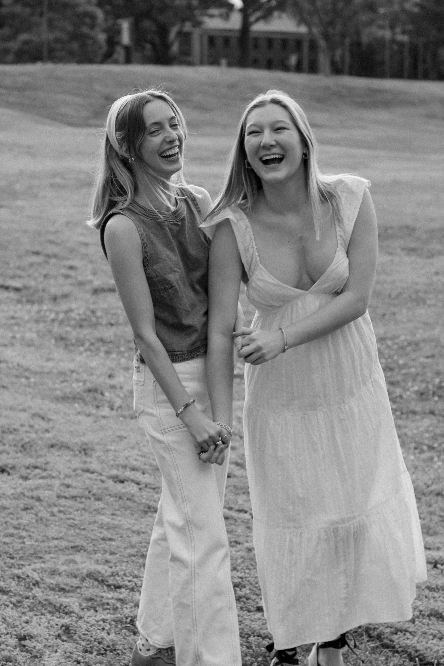 Two friends share genuine laughter together outdoors in black and white photography.
