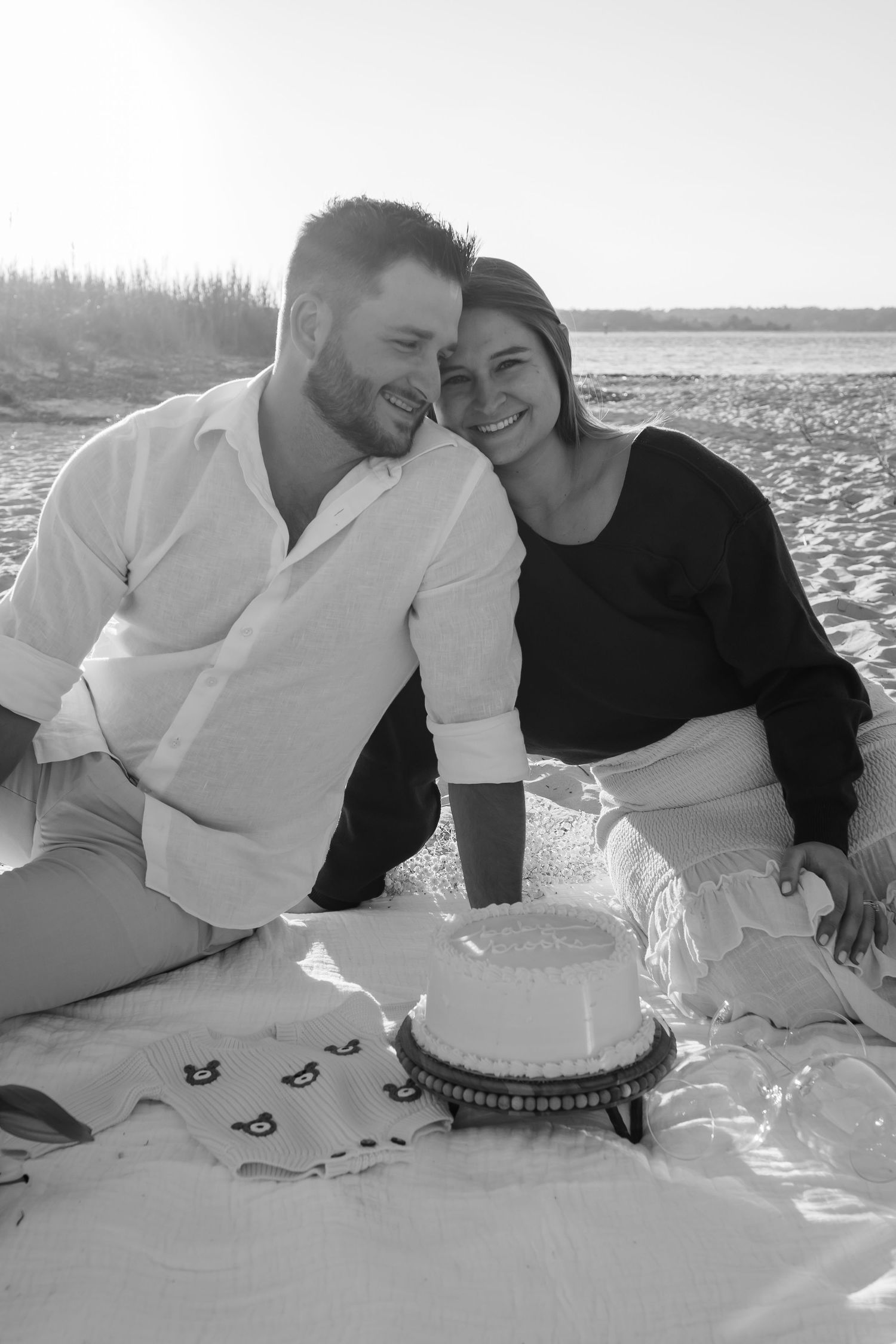 Black and white beach picnic scene with couple and small cake.