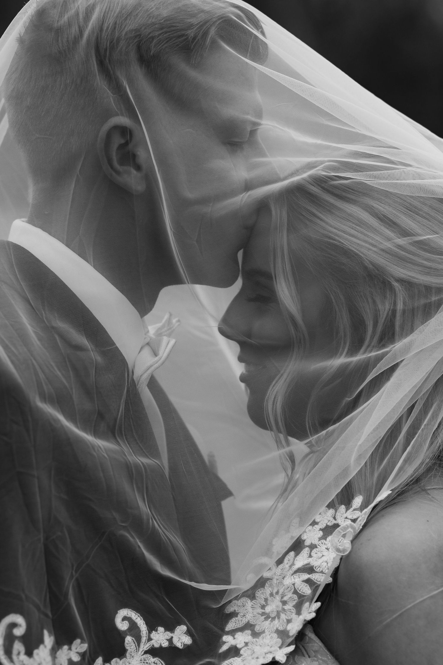 Dramatic black and white bridal portrait with delicate lace veil details.