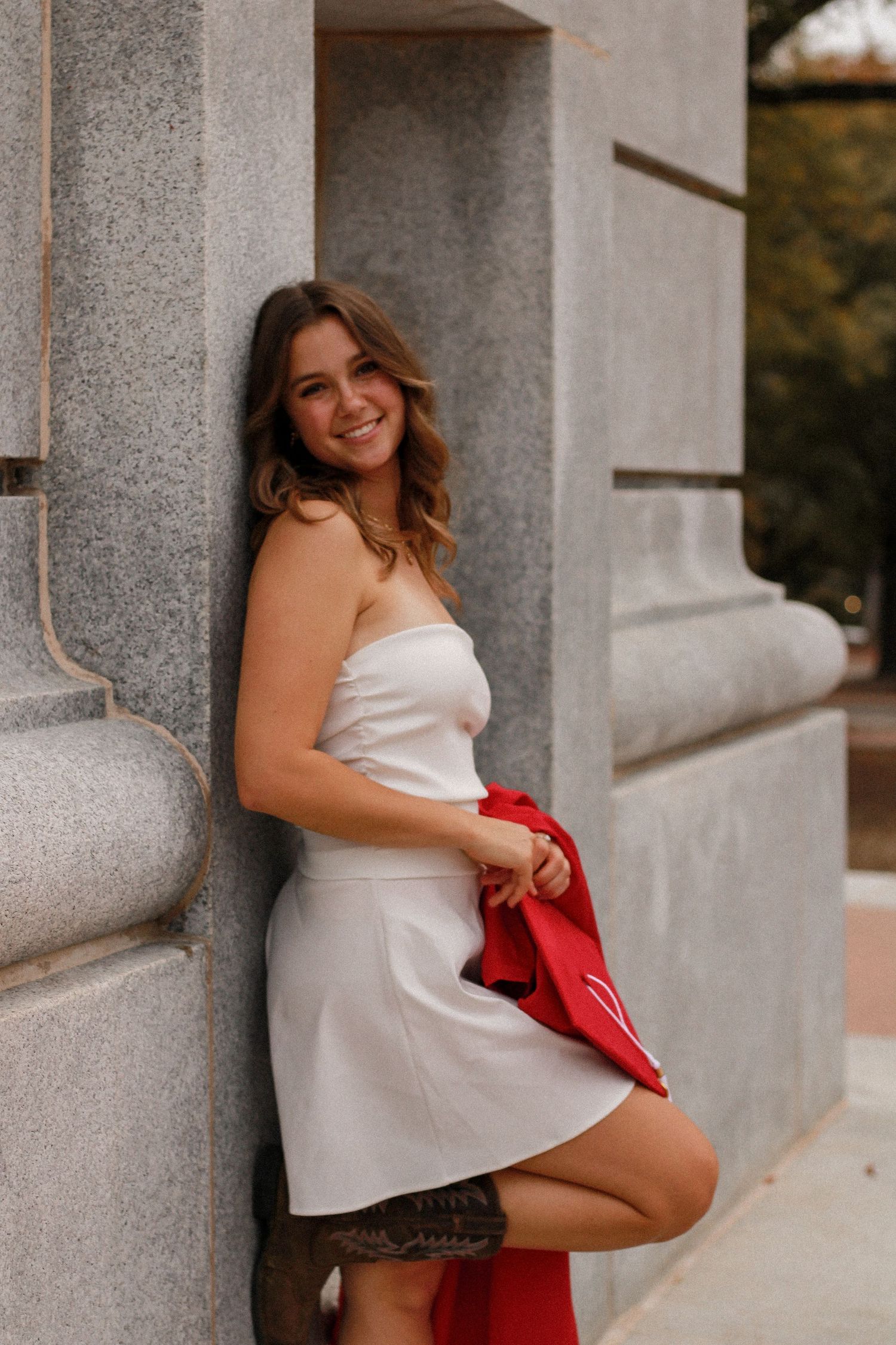 Portrait series featuring someone in white dress and red jacket posing against stone architecture.