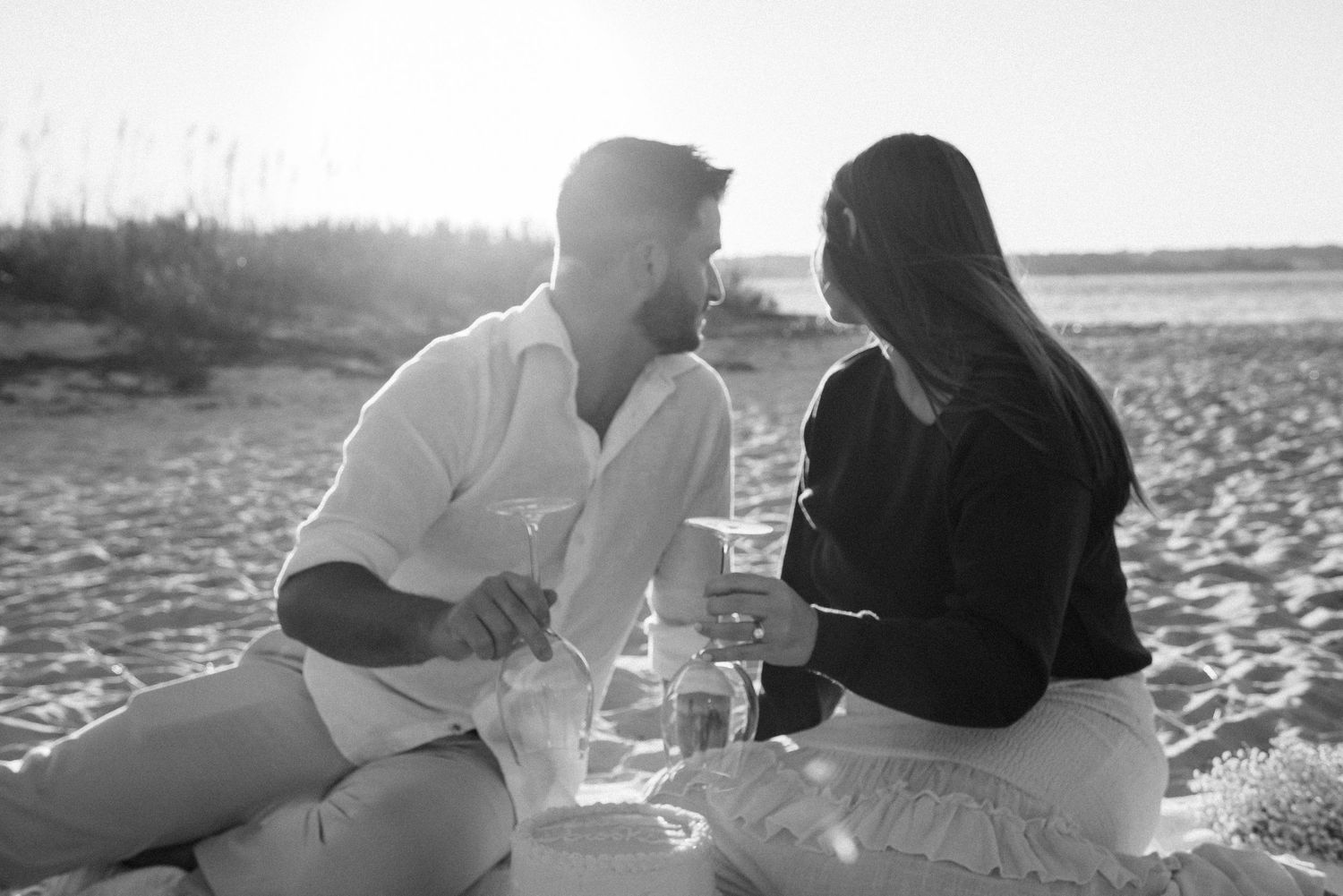 Couple sharing intimate moment during sunset beach picnic.