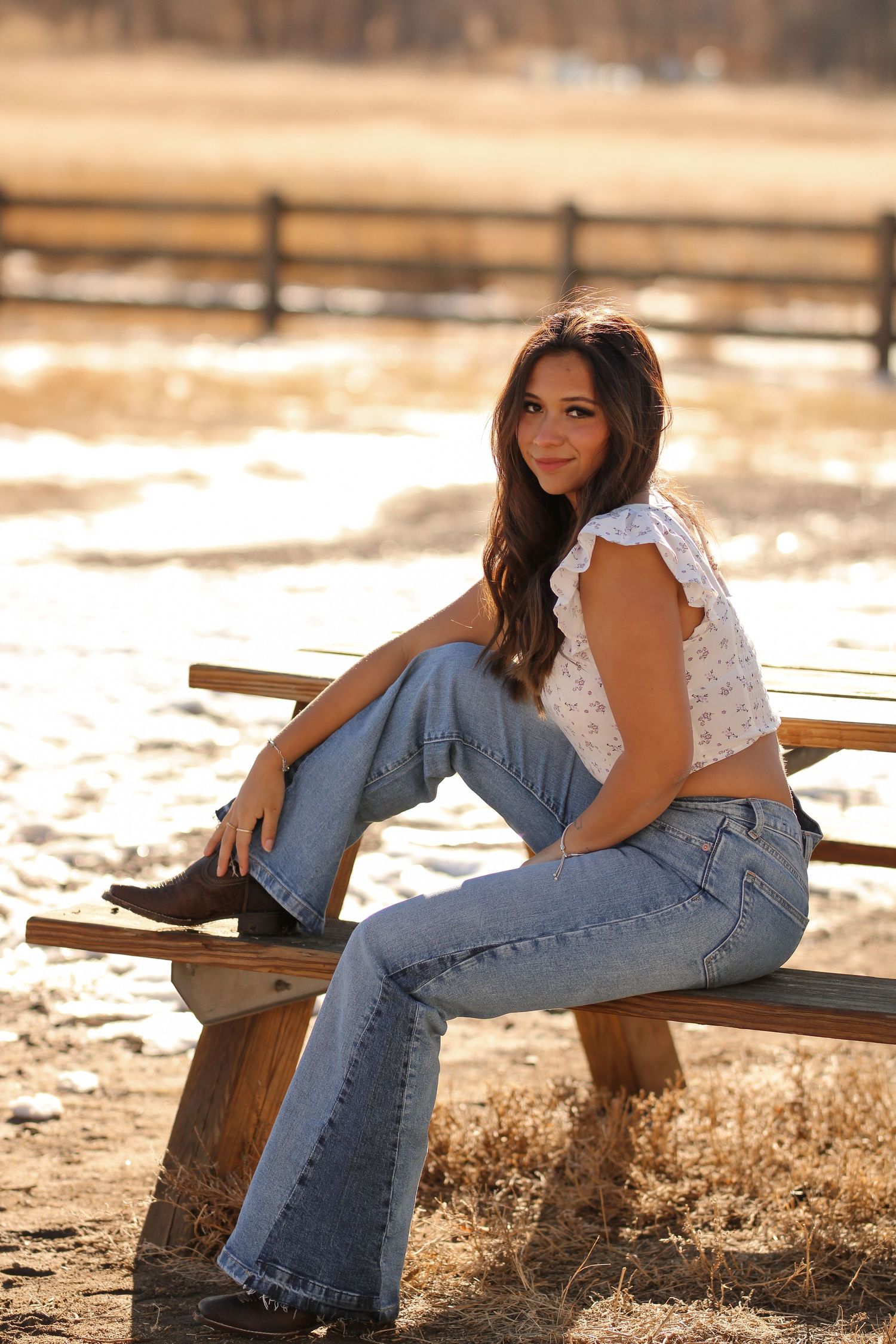 Casual fashion poses on wooden bench in countryside setting.