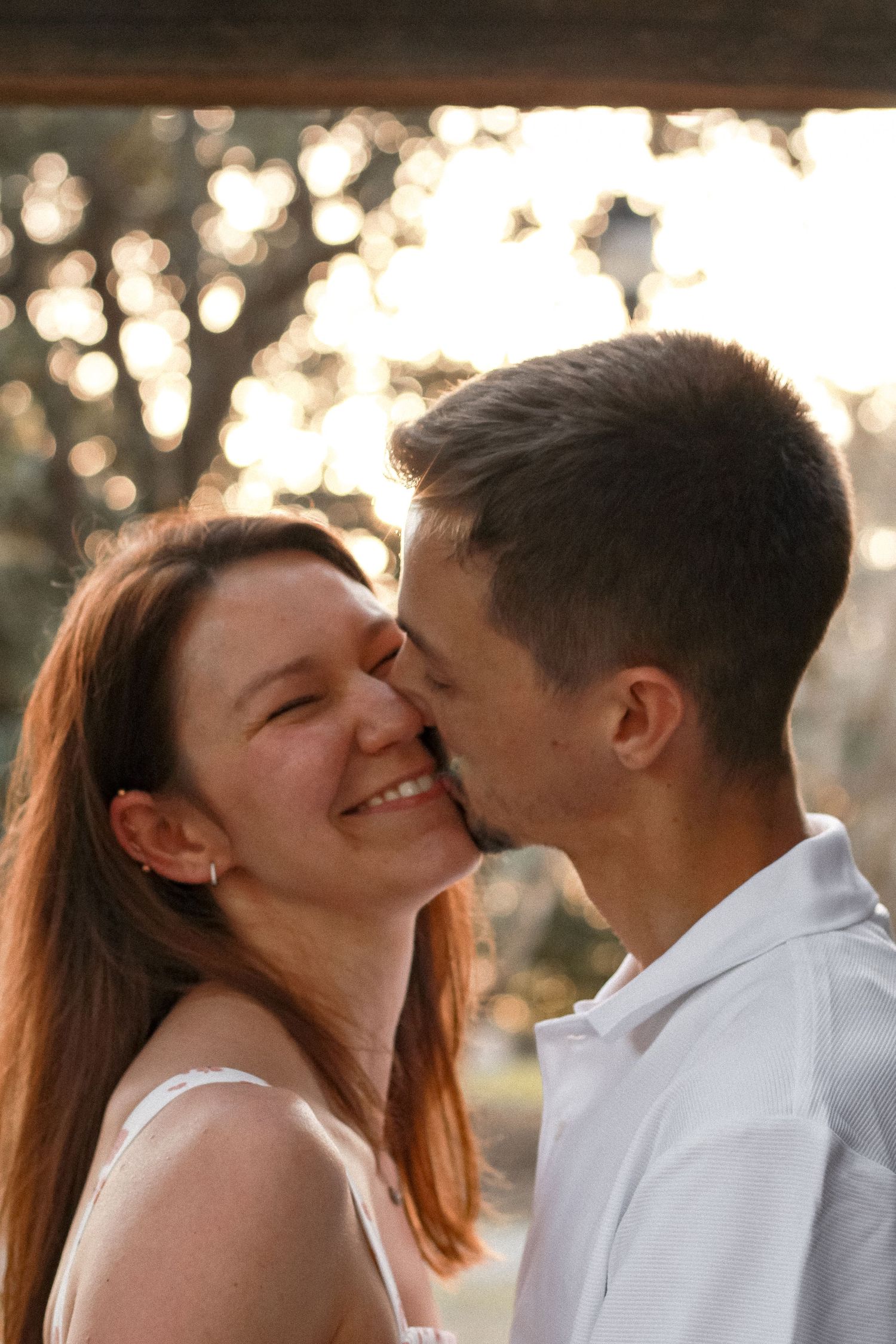 An intimate moment between a couple sharing laughter and affection at sunset.
