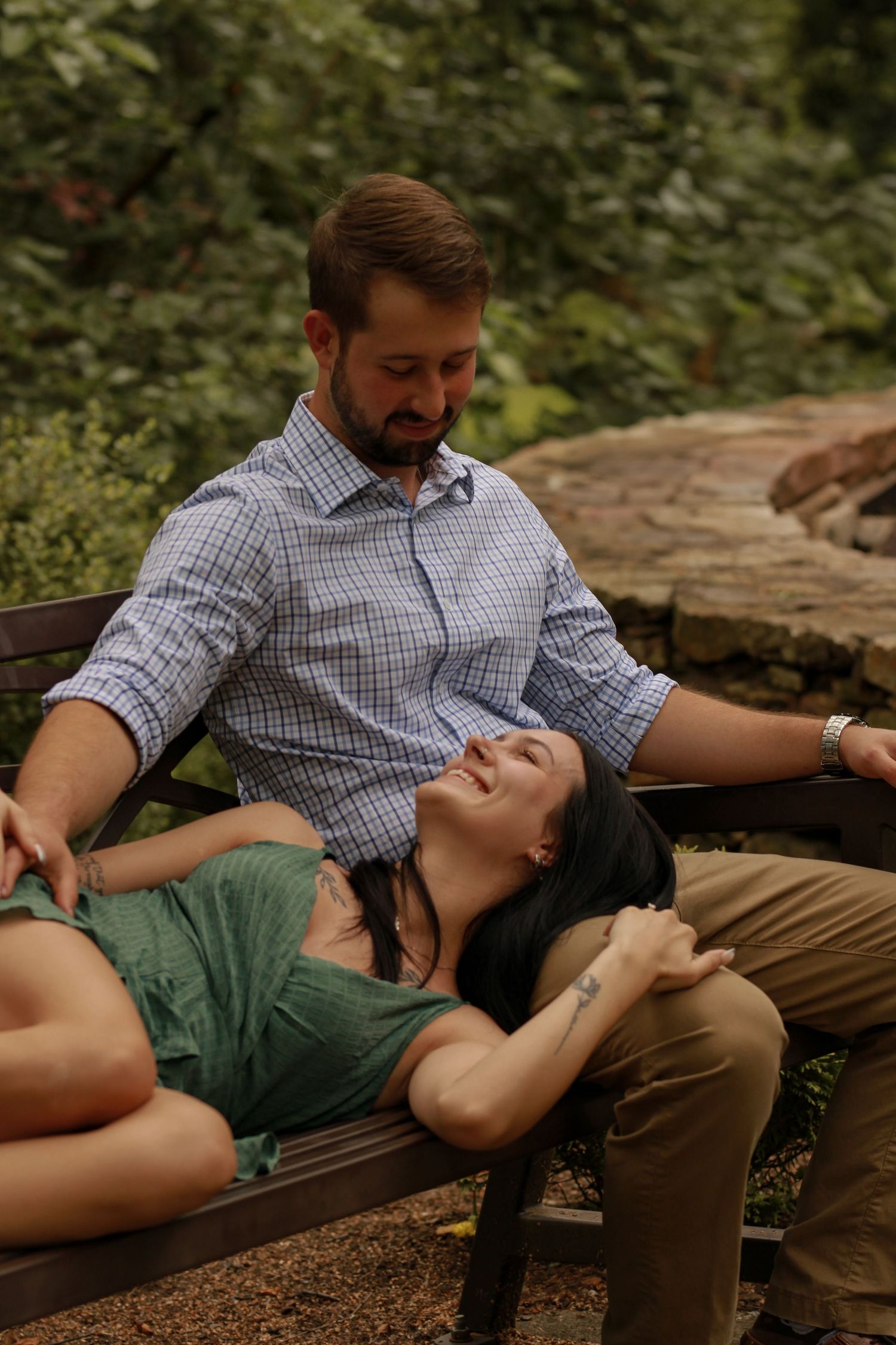 Couple sharing intimate moments while lounging on a rustic wooden bench outdoors.