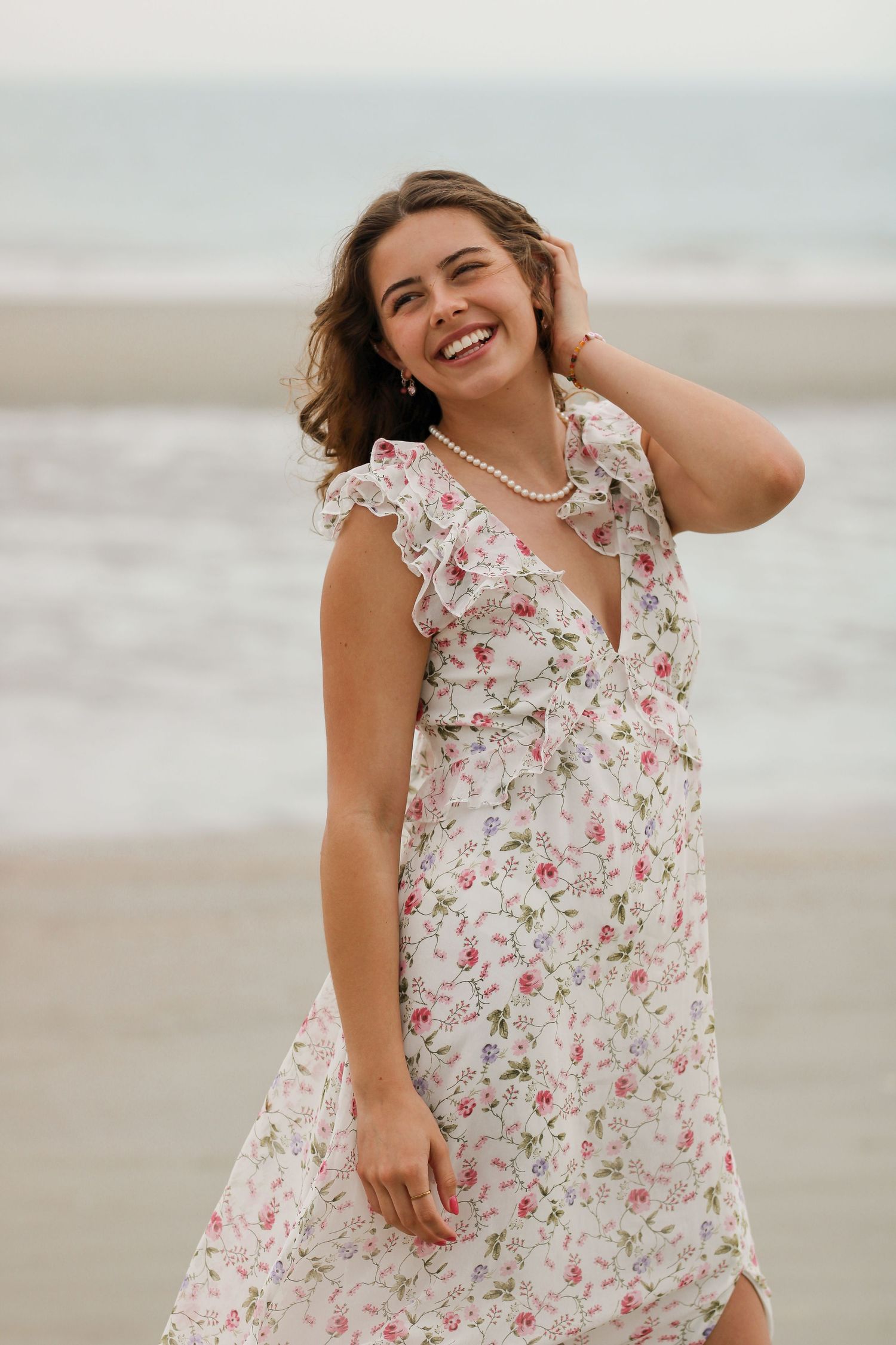 A joyful beach portrait in a romantic floral dress with ruffled details.