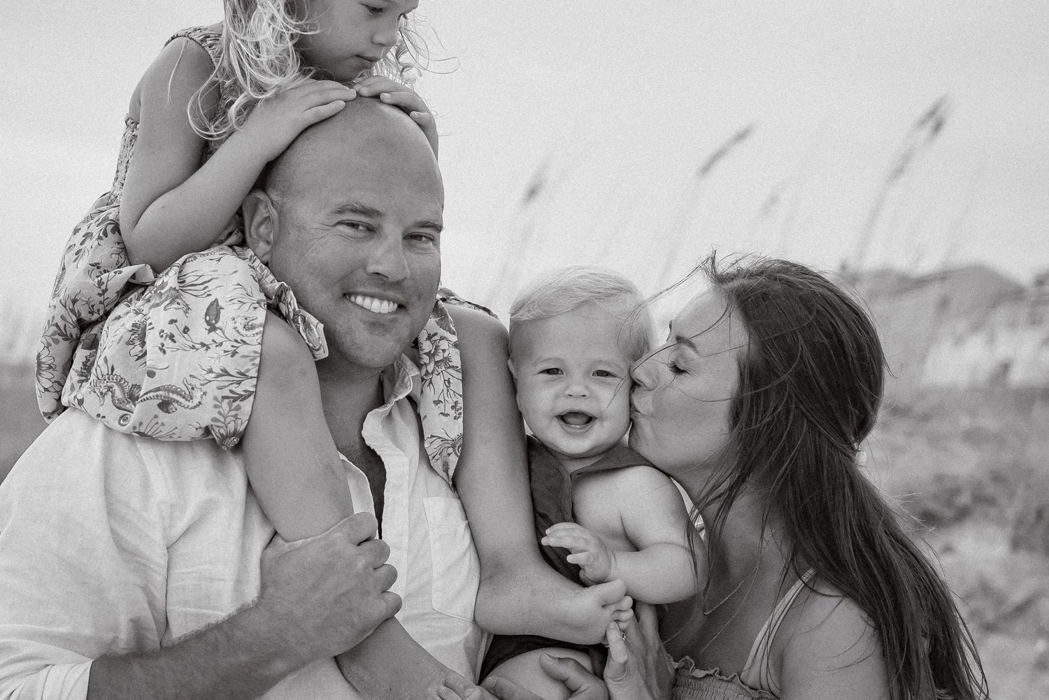A joyful family photoshoot with playful interactions on the beach.