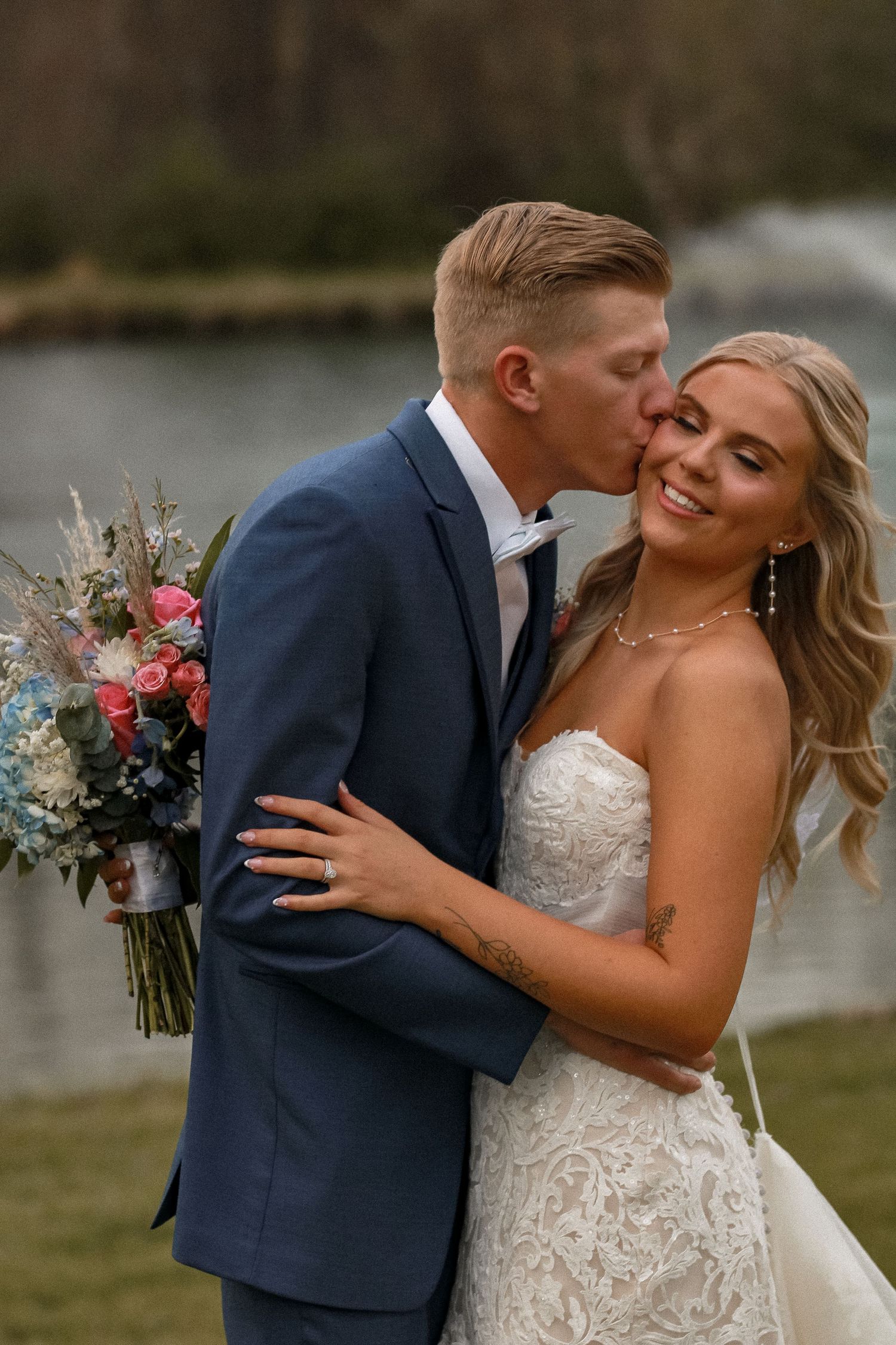 A romantic wedding photo series showing a couple embracing outdoors with the bride in a lace dress and groom in navy suit.