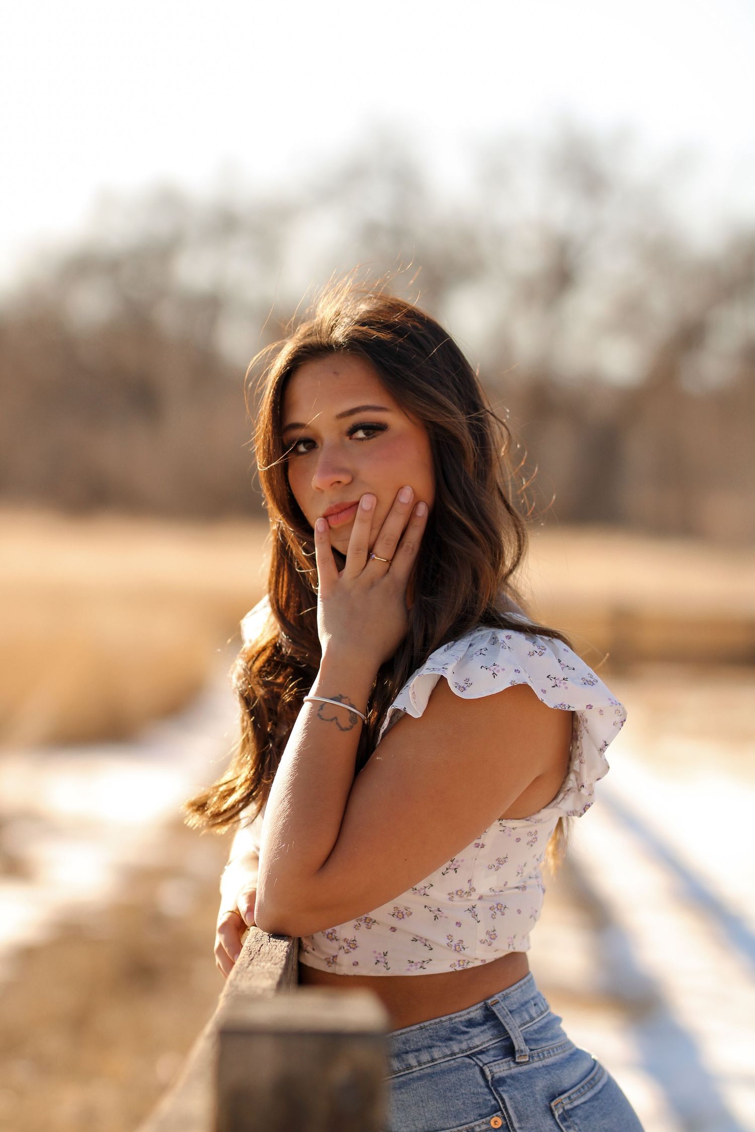 Outdoor fashion portraits with floral top and denim in warm sunlight.