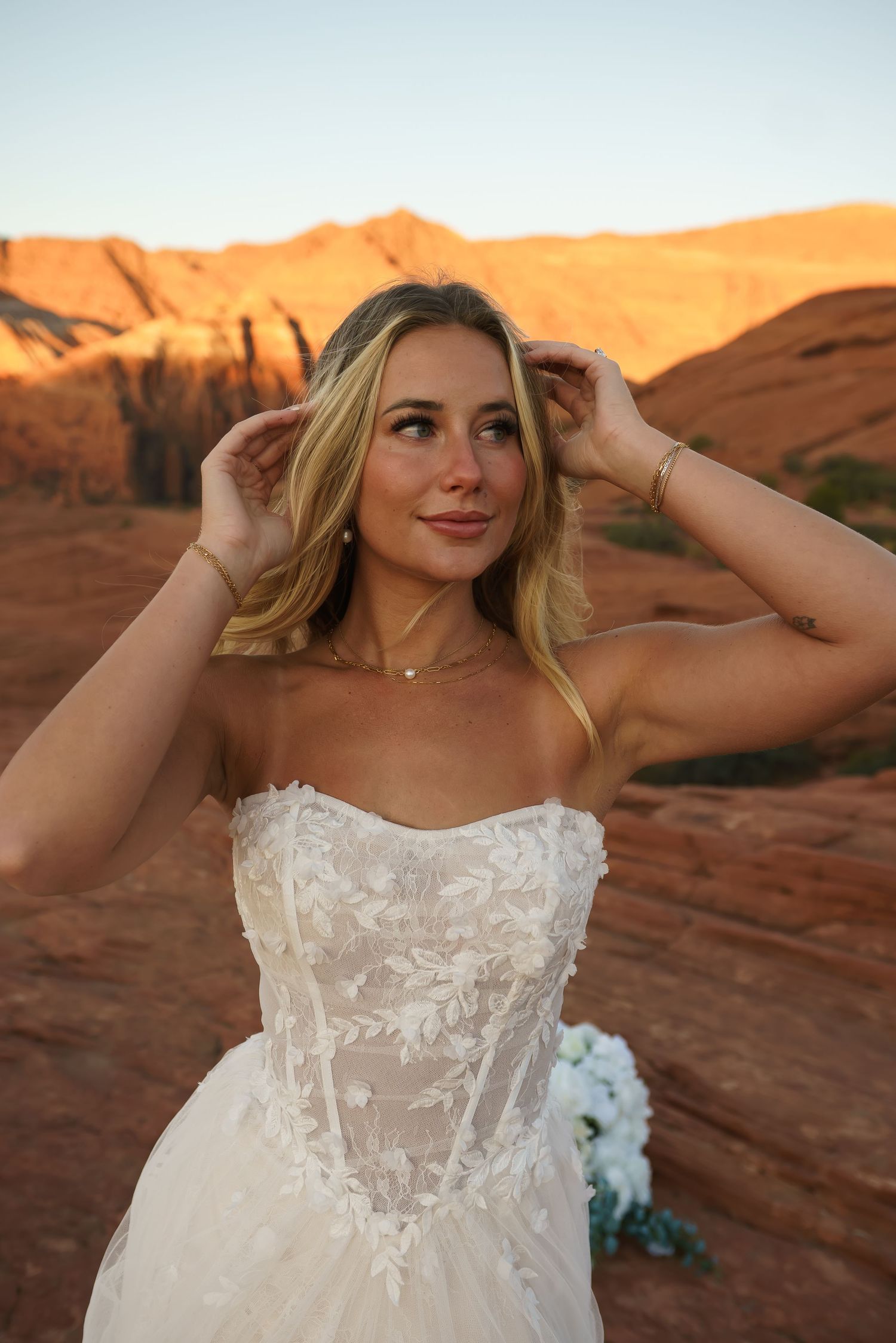 Close-up shots of a bride in a detailed white lace dress against red rock cliffs at sunset.