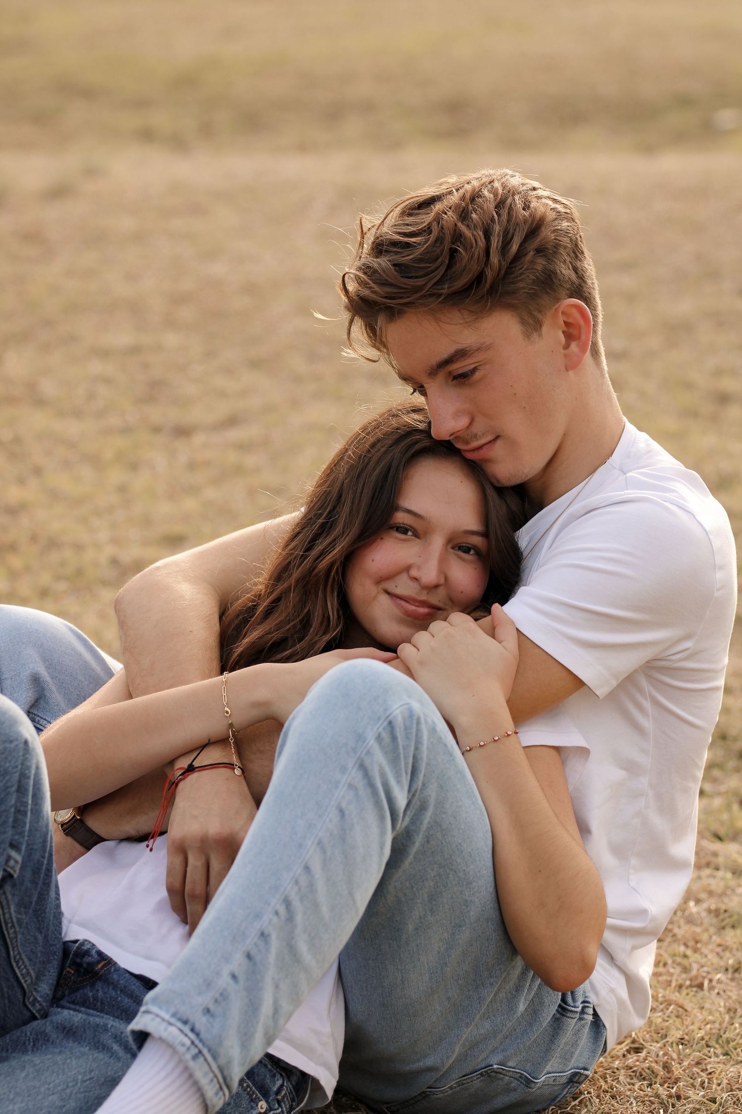 A tender embrace on grass during golden hour.