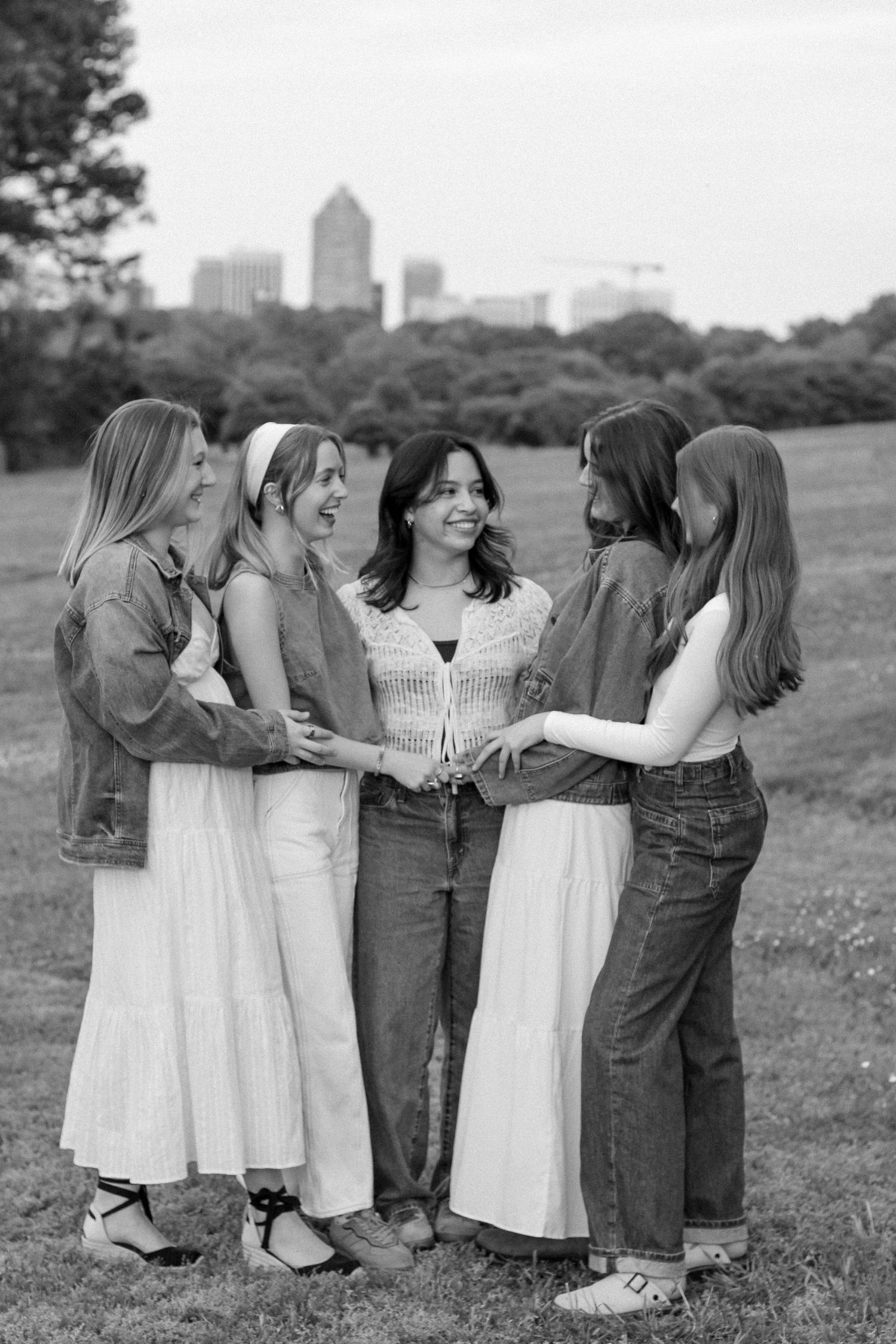 Group photo of people in white dresses and denim standing together against a city skyline.