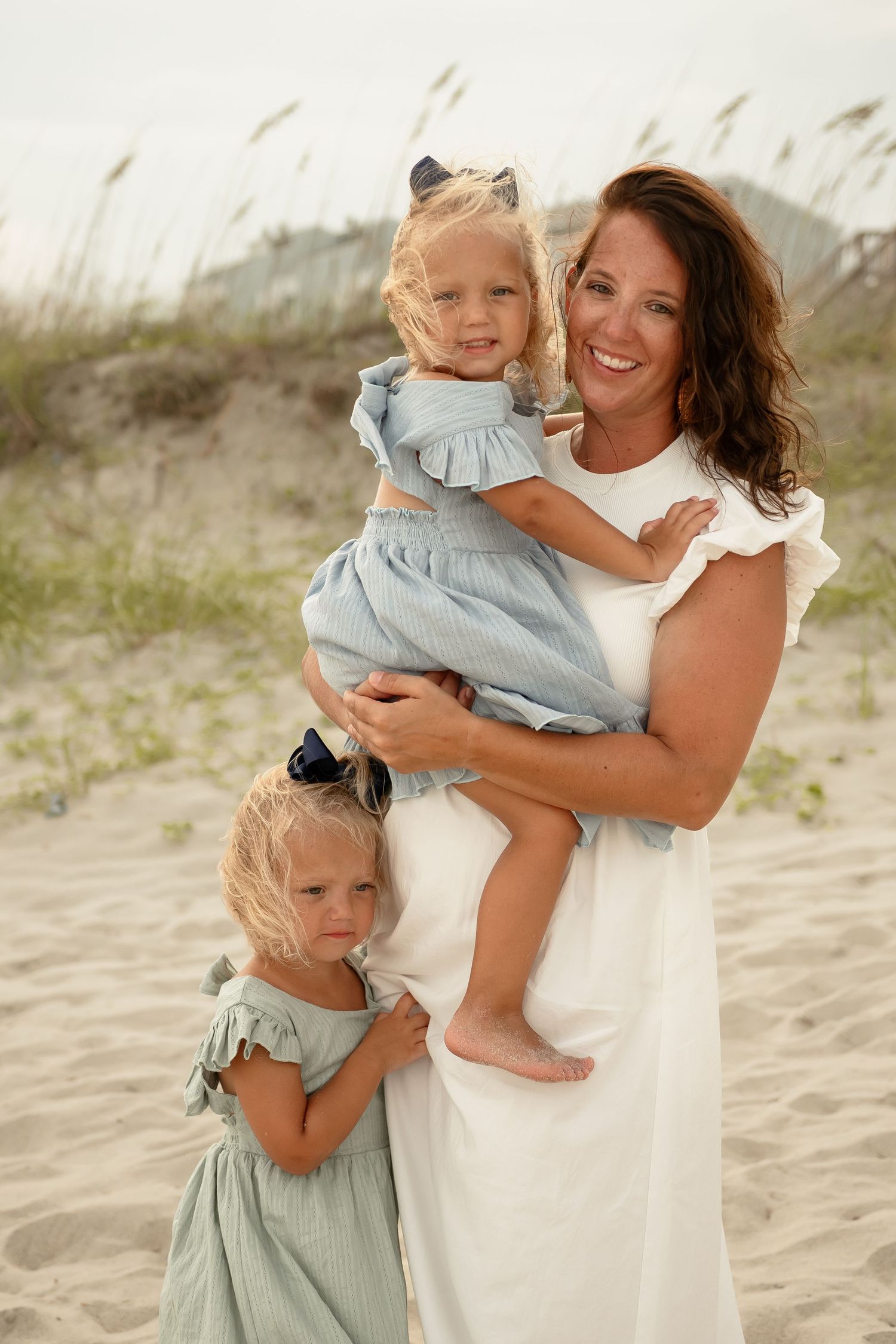 Family portrait sequence showing mother with children in matching blue dresses on sandy beach.