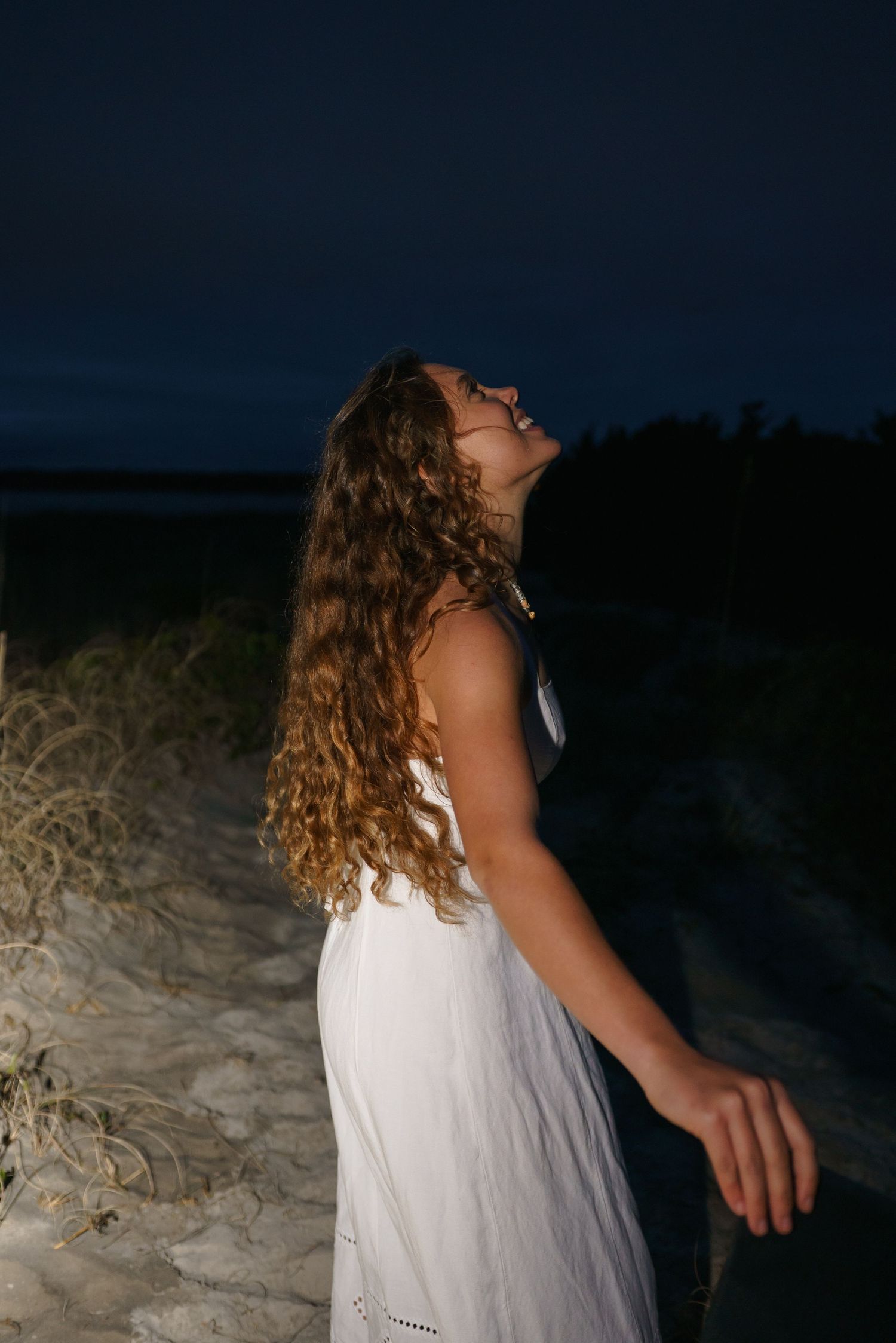 Artistic nighttime graduation photos taken on a beach with dramatic lighting.