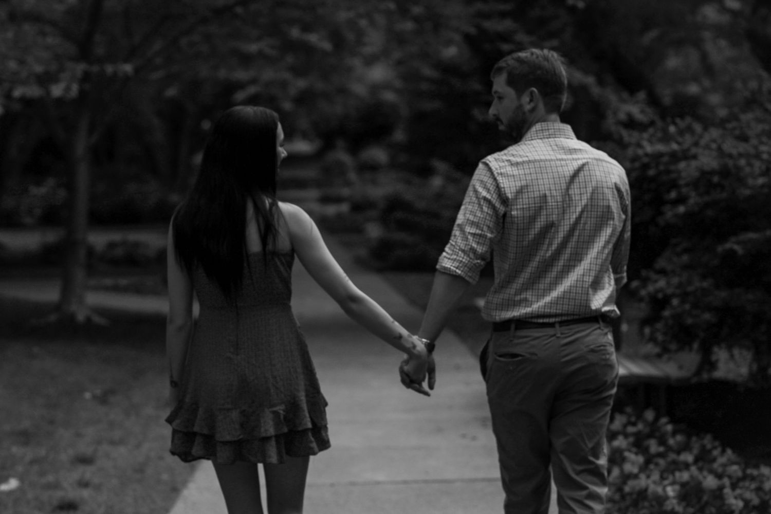 Silhouette of a couple walking together on a tree-lined path.