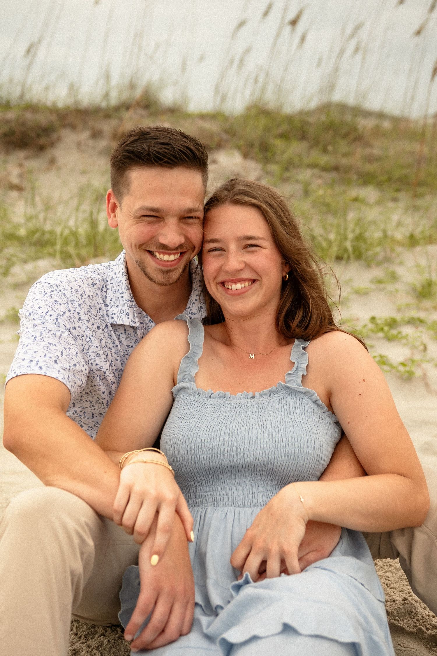 Romantic beach portraits featuring a couple in coordinating outfits against coastal scenery.