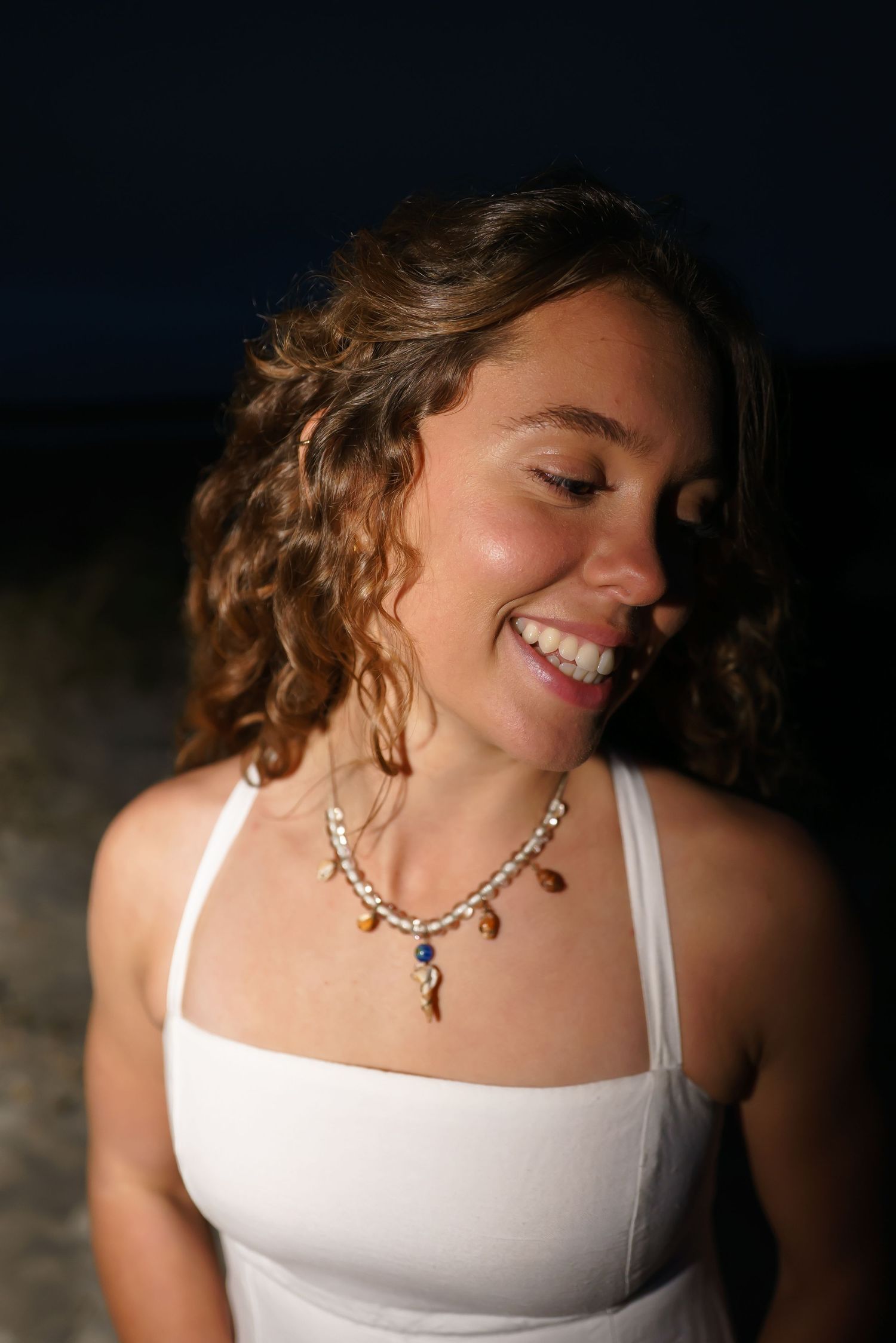 Close-up portrait shots highlighting a silver necklace and white graduation dress.