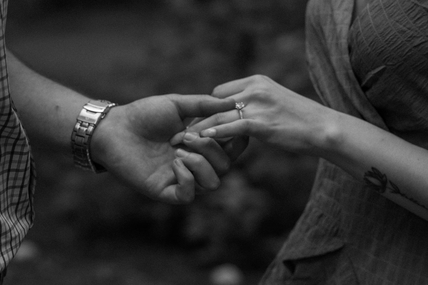 Artistic black and white photo of hands with rings intertwined.