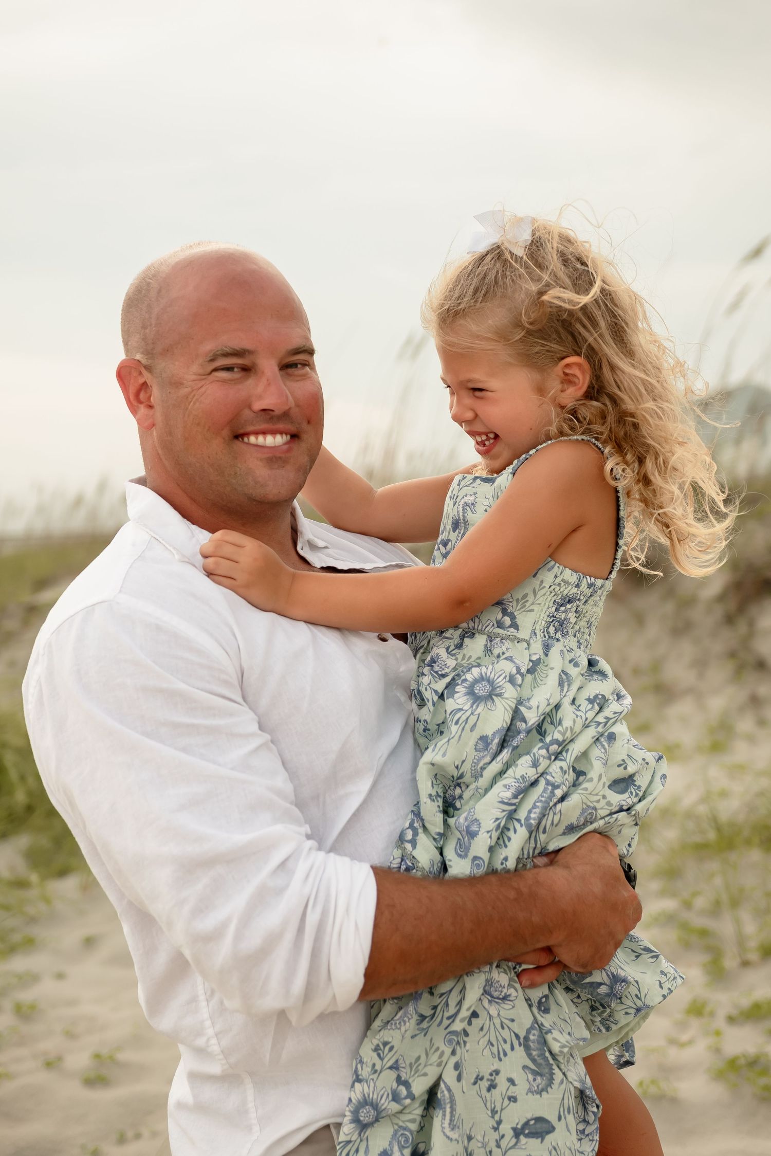 Candid shots of a father and daughter sharing happy moments on a sandy beach.