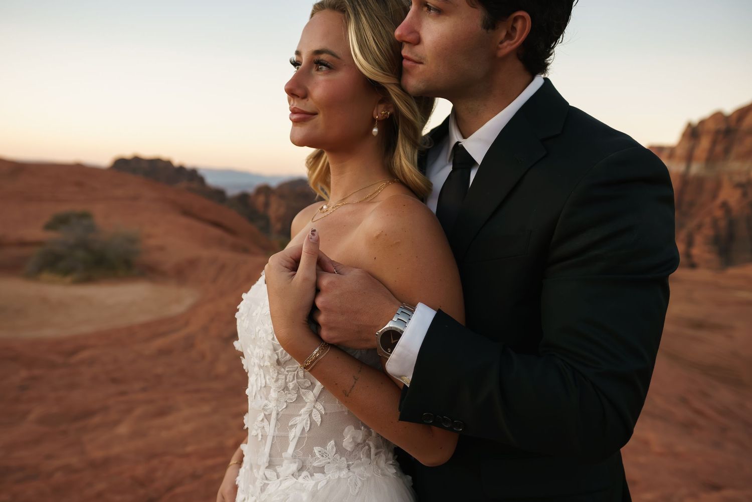 Romantic wedding portrait with desert mountains in background during golden hour.