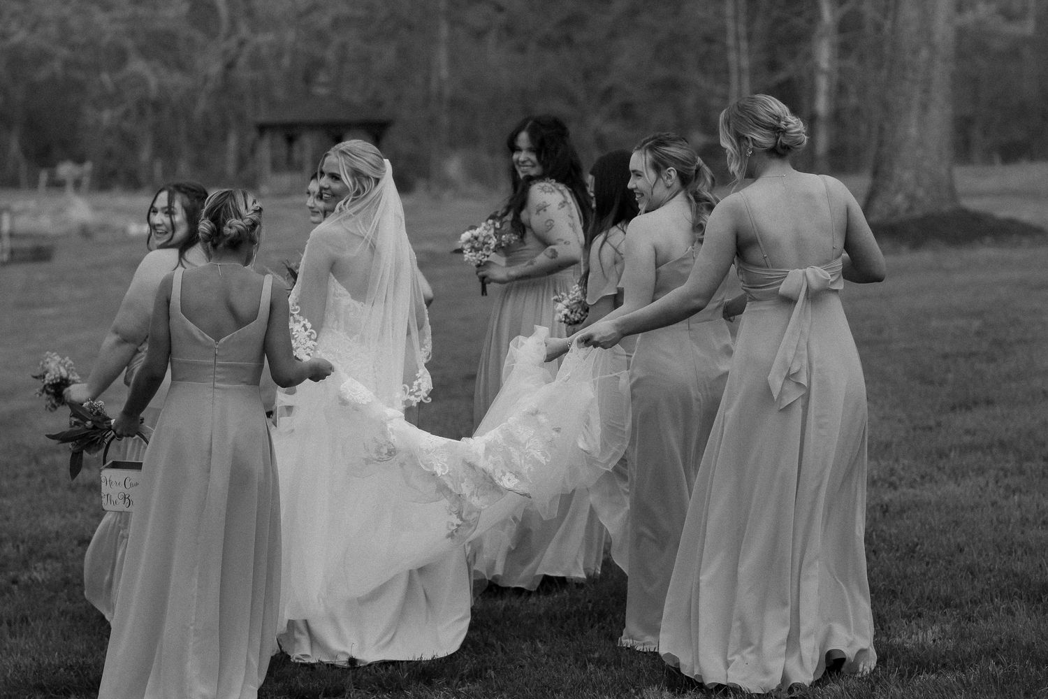 Bridesmaids in light colored dresses celebrating at an outdoor wedding.