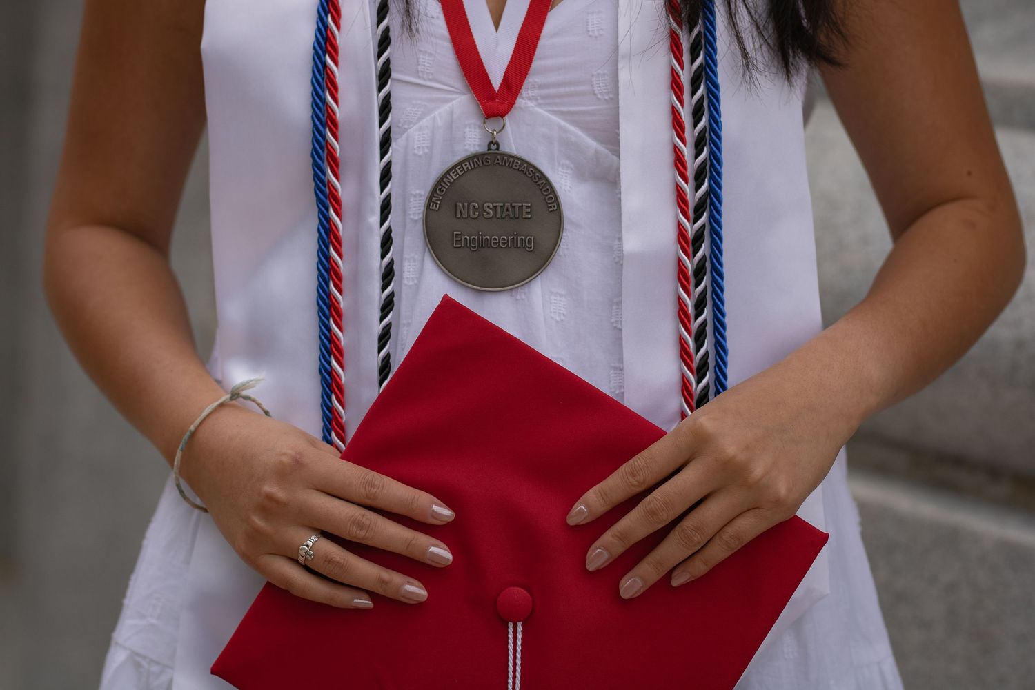 Close-up of graduation regalia showing red stole and braided honor cords.