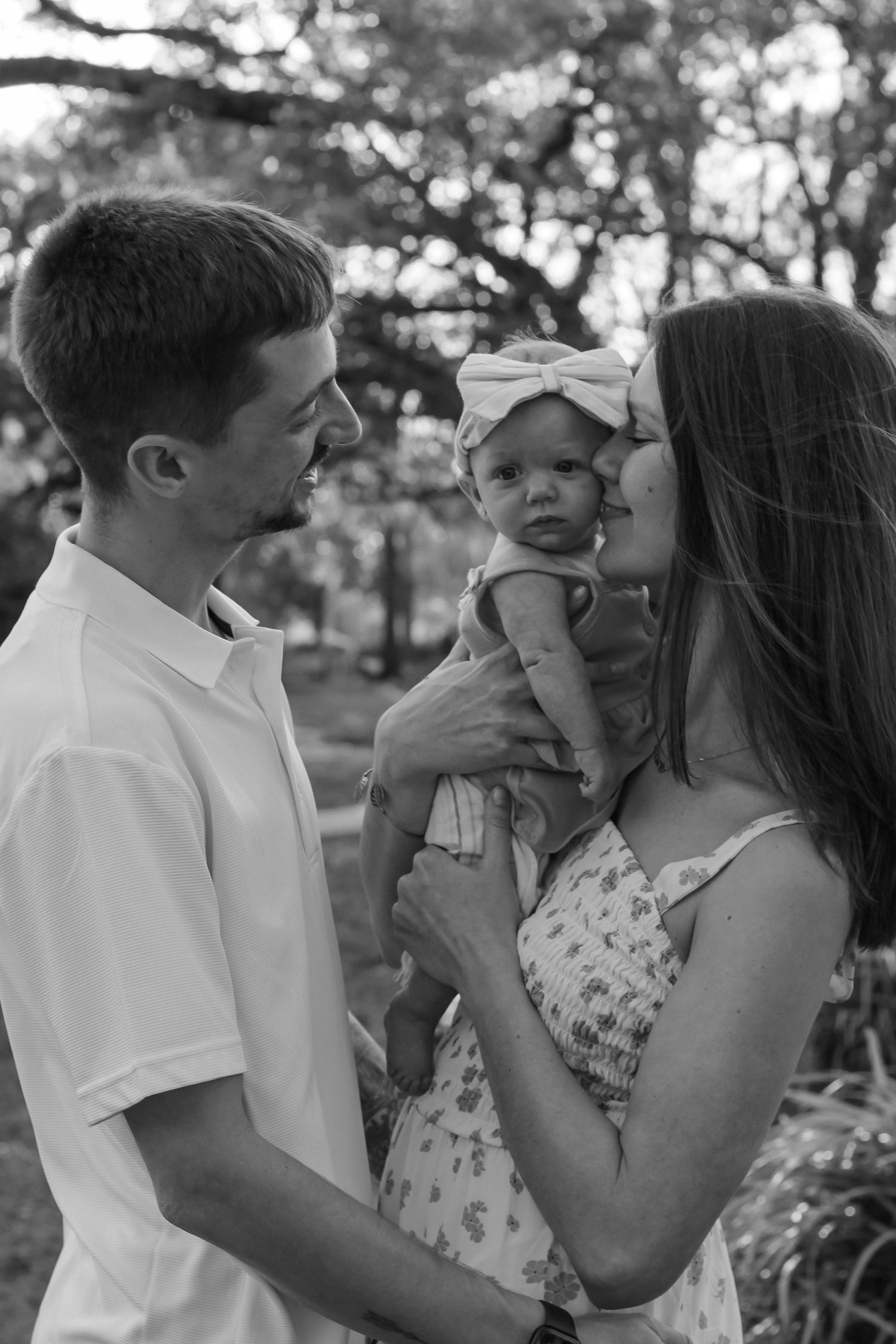 Black and white family photos showing tender moments between parents and their baby.