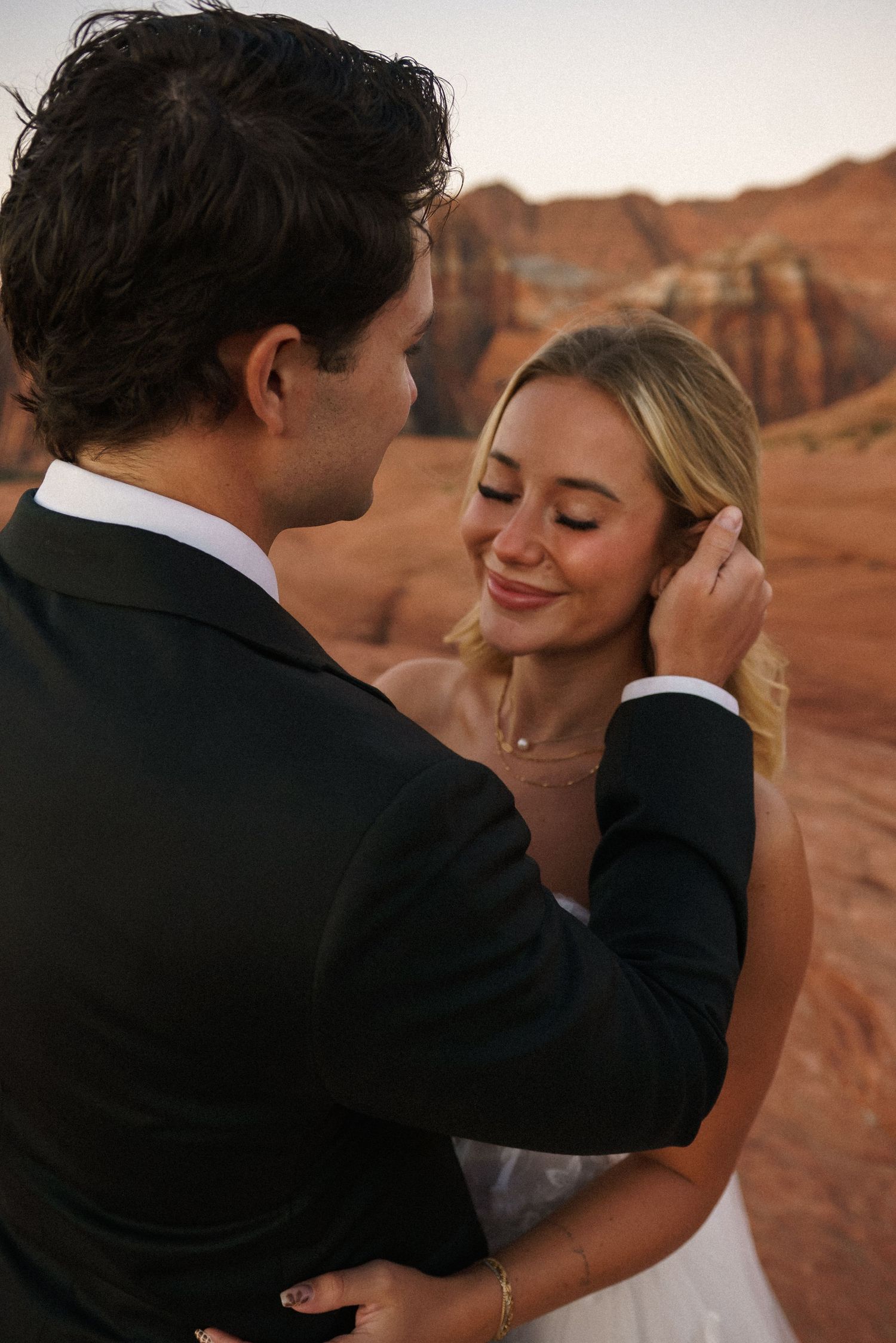 Intimate wedding moment captured against stunning desert canyon backdrop.