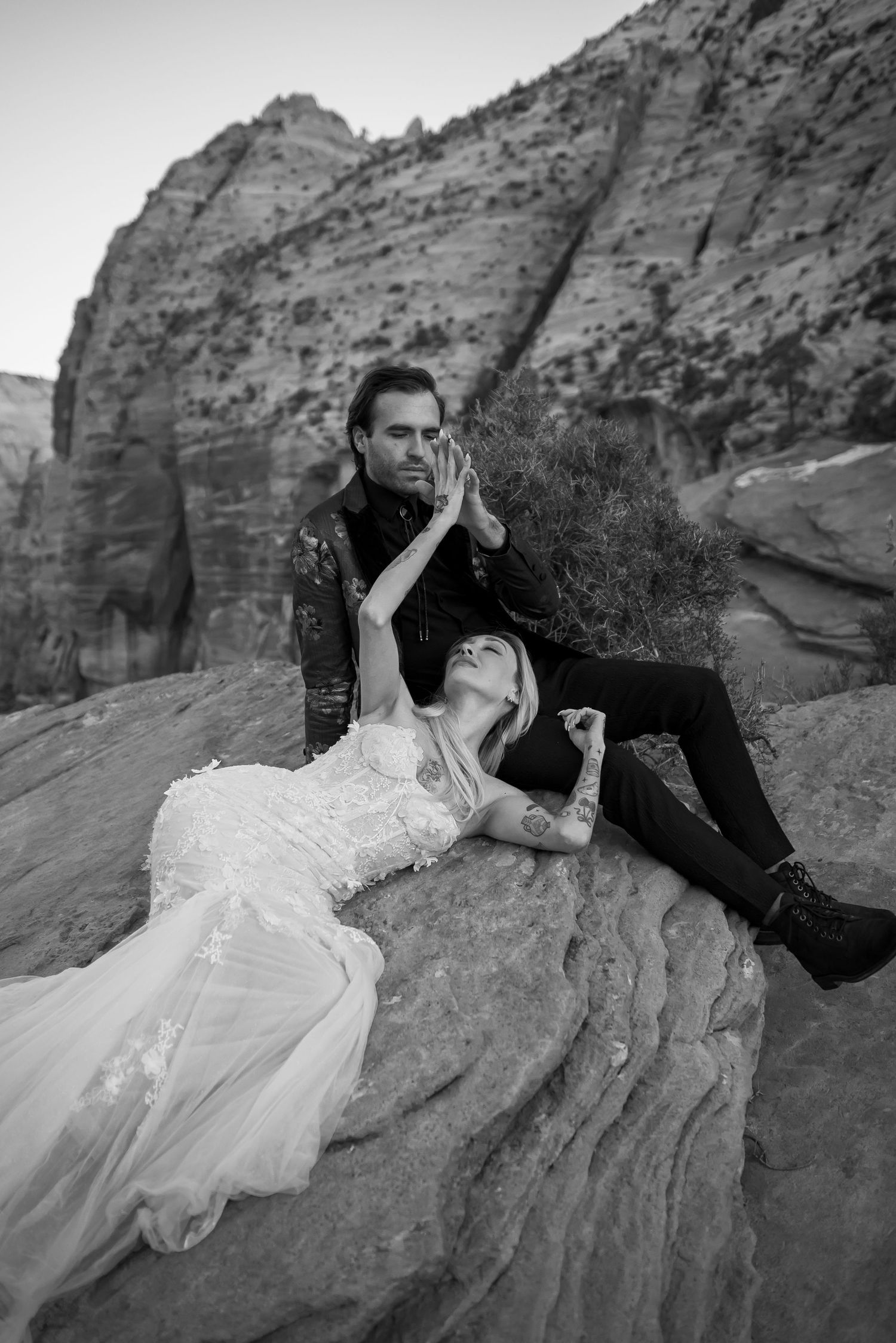 Artistic black and white wedding photos on layered rock formations in a desert setting.