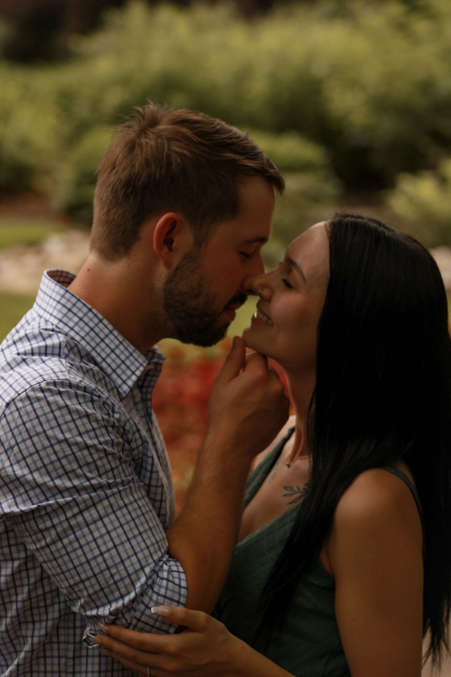 A tender romantic moment captured between a couple in a natural outdoor setting.